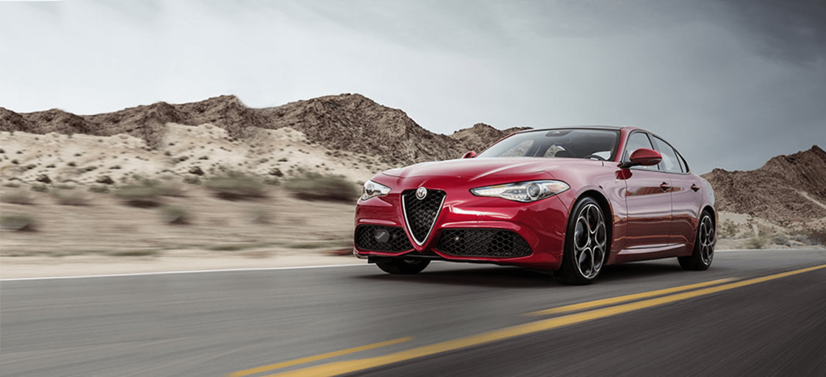 Front view of a red 2022 Alfa Romeo Giulia driving down a road.