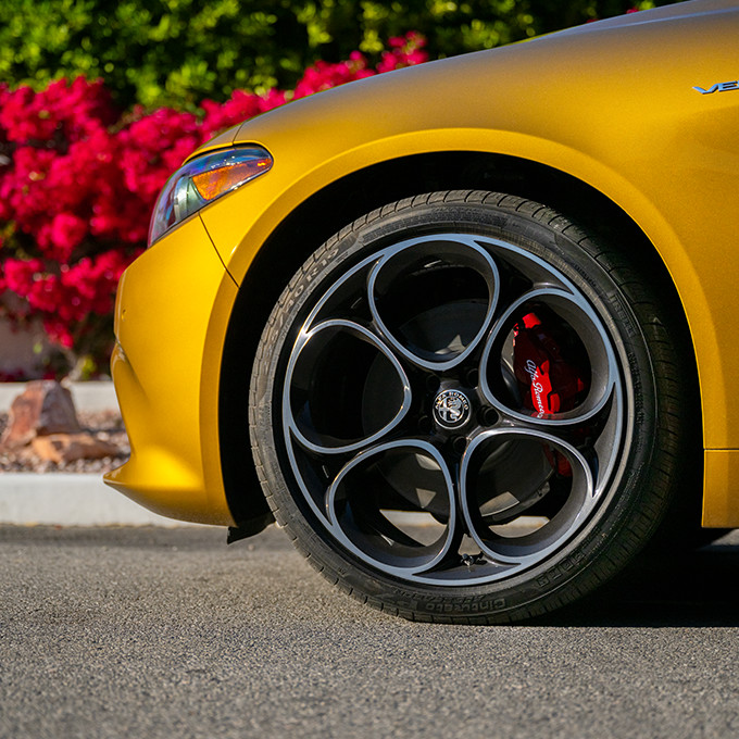 A closeup of the front driver side wheel of a yellow 2023 Alfa Romeo Giulia.