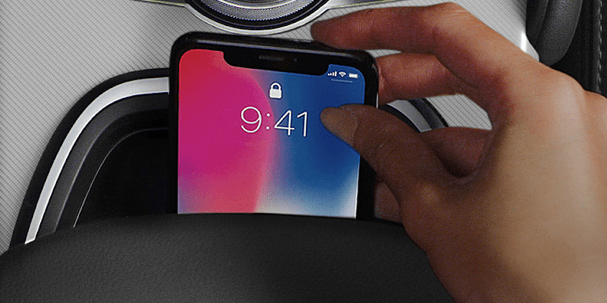 Vue intérieure d'un véhicule Alfa Romeo 2025 présentant la fonction de chargement sans fil. L'image met en évidence une main posant un téléphone intelligent sur le socle de chargement intégré à la console centrale.