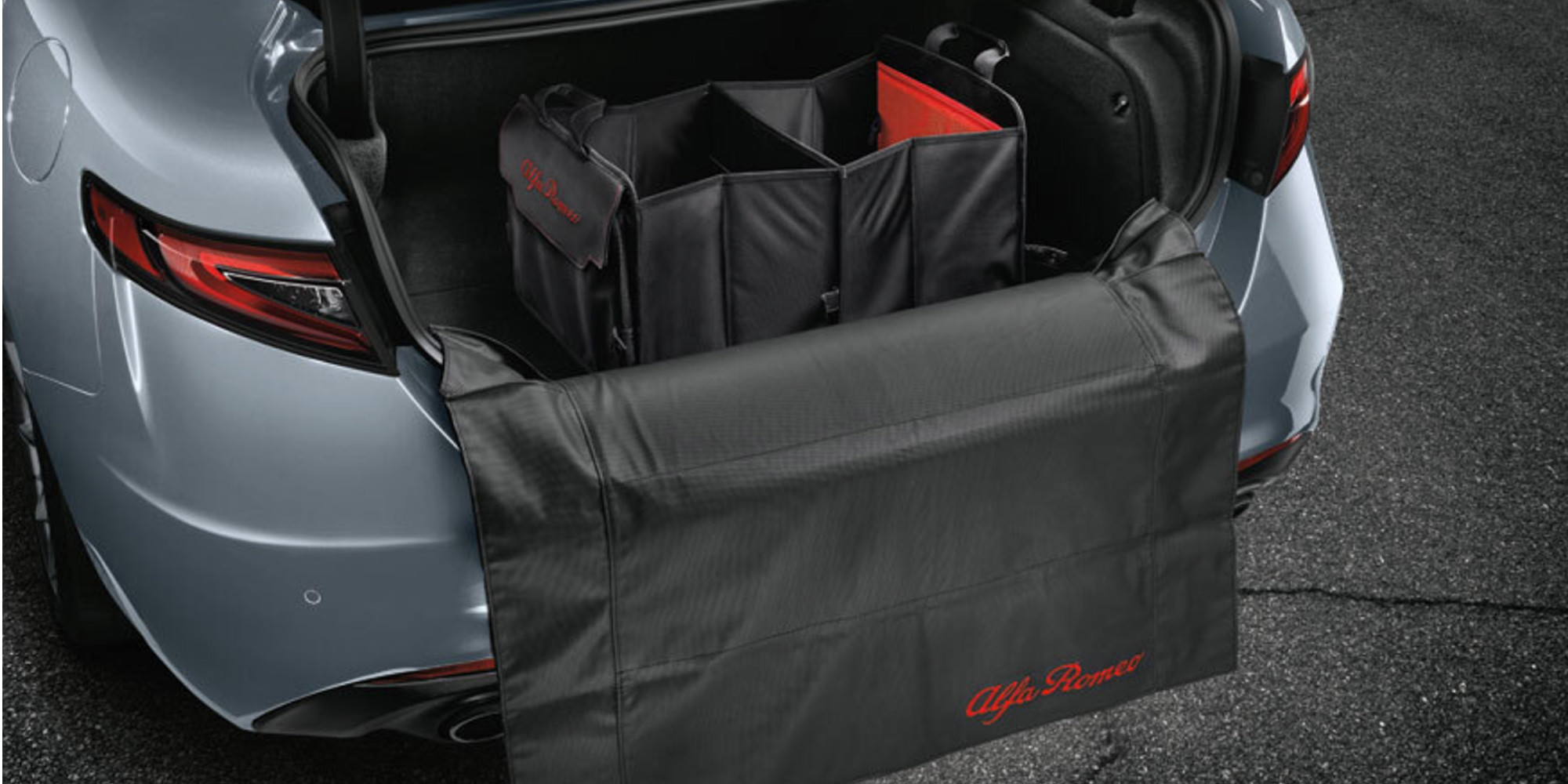 Le coffre d'un véhicule Alfa Romeo 2025, présentant un espace de chargement spacieux avec un système de rangement organisé. Le coffre ouvert révèle un couvercle de protection et des compartiments soigneusement agencés.