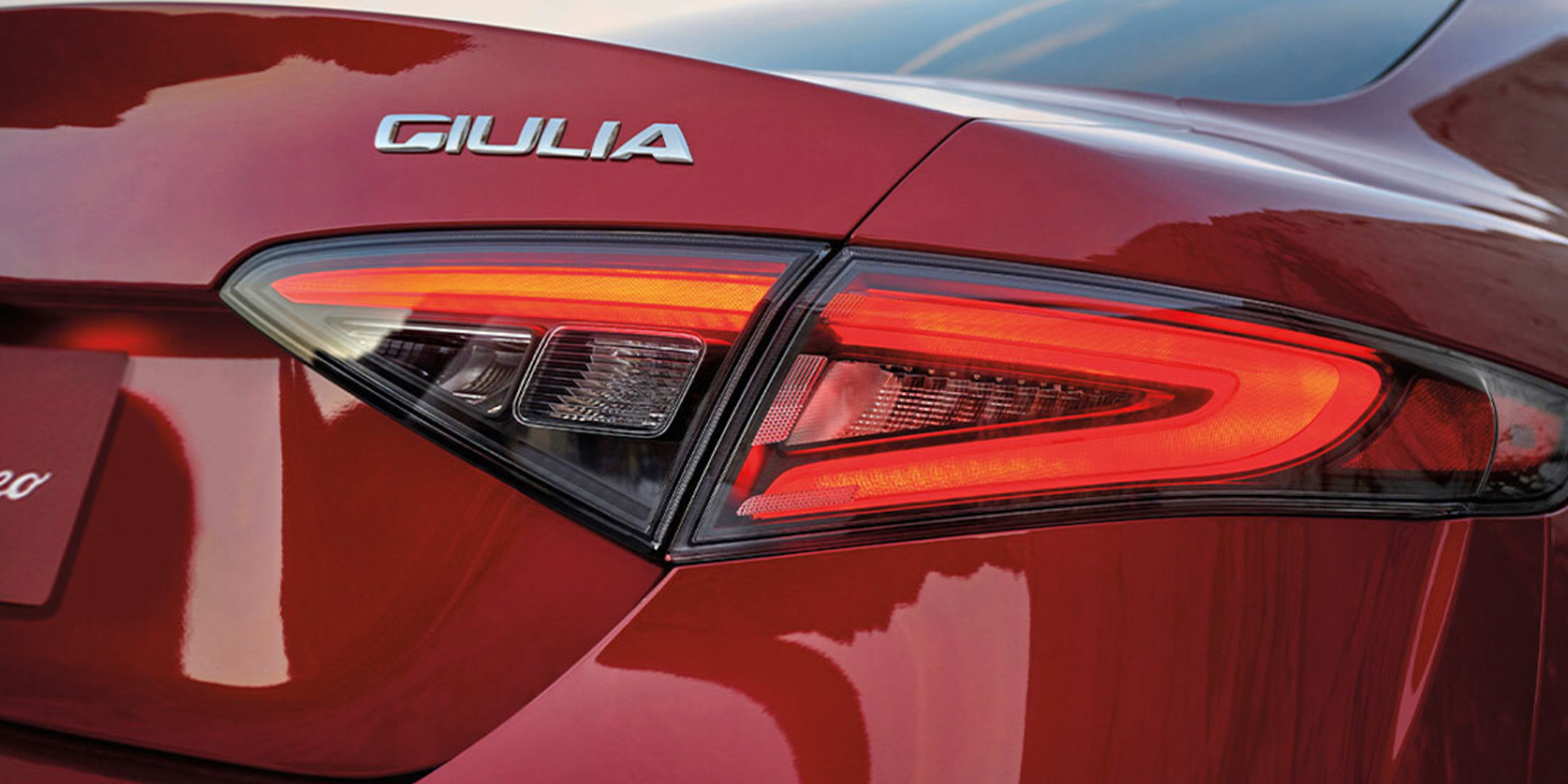 Gros plan d'une Alfa Romeo Giulia rouge 2025, se concentrant sur le feu arrière et l'emblème Giulia.