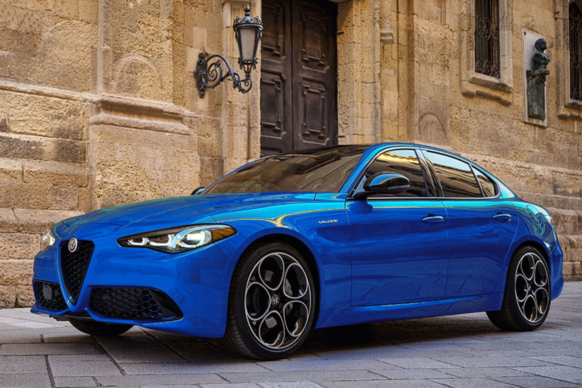 Anodized Blue Metallic 2025 Alfa Romeo Giulia parked on a cobblestone street with stone buildings in the background.