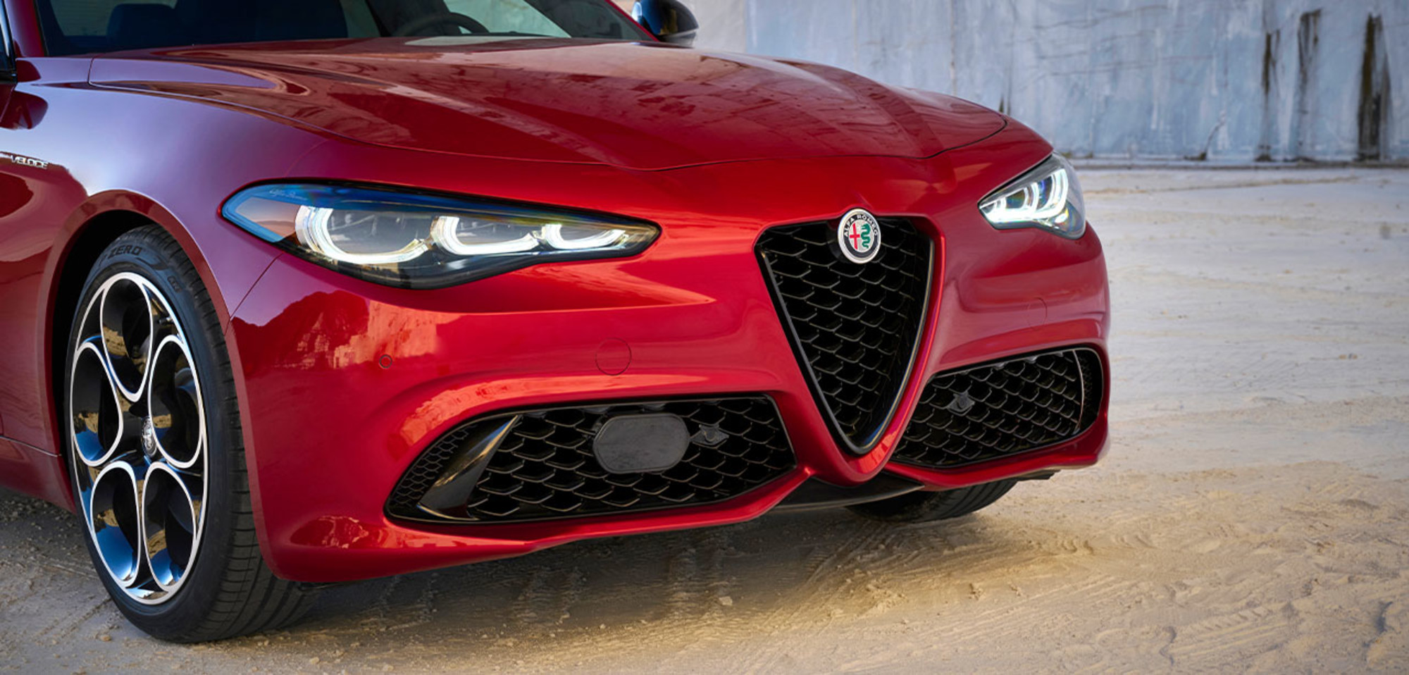 Front view of an Alfa Rosso 2025 Alfa Romeo Giulia, showcasing its distinctive grille and sleek headlights.