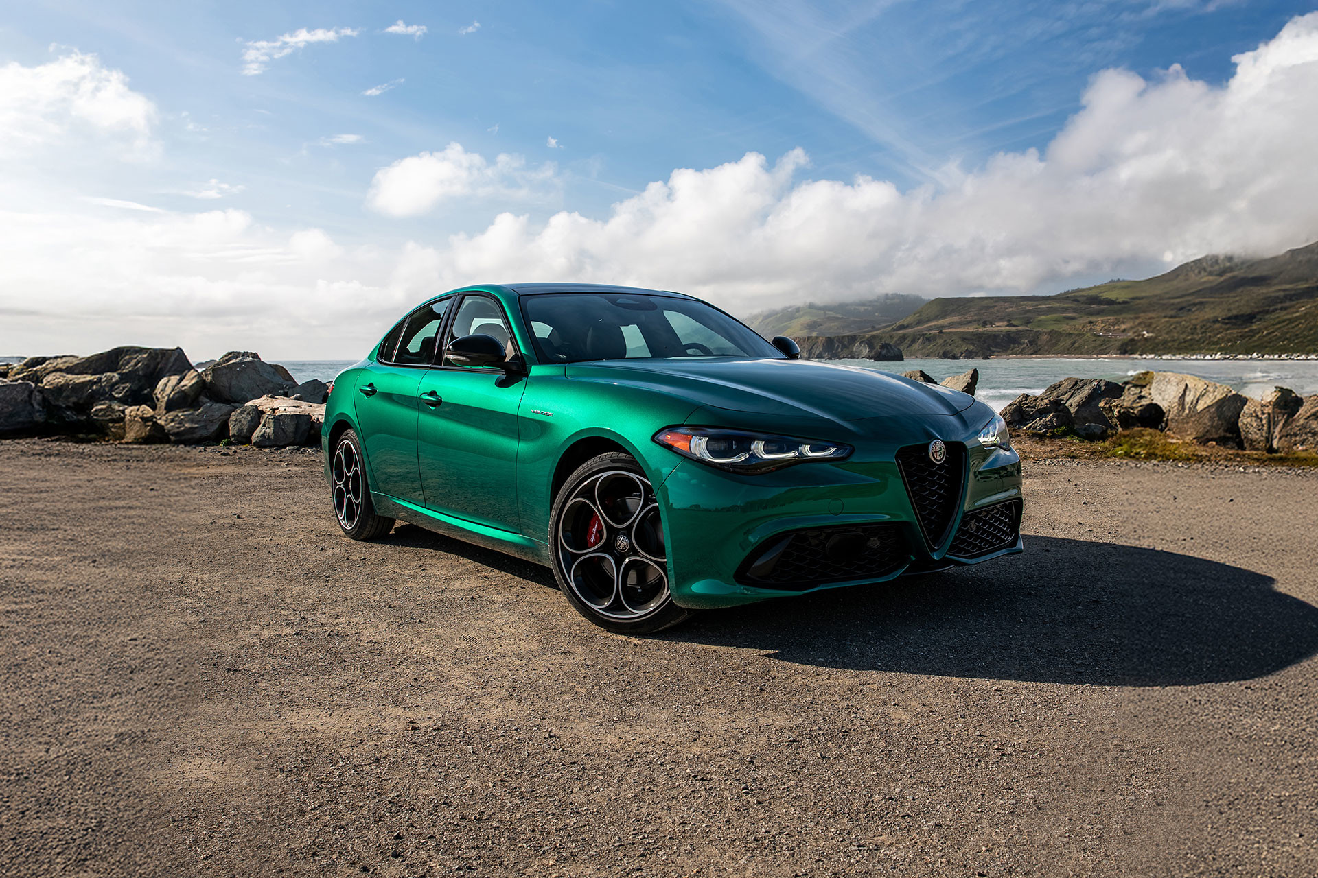 Green 2026 Alfa Romeo Giulia parked by the ocean under a clear blue sky.