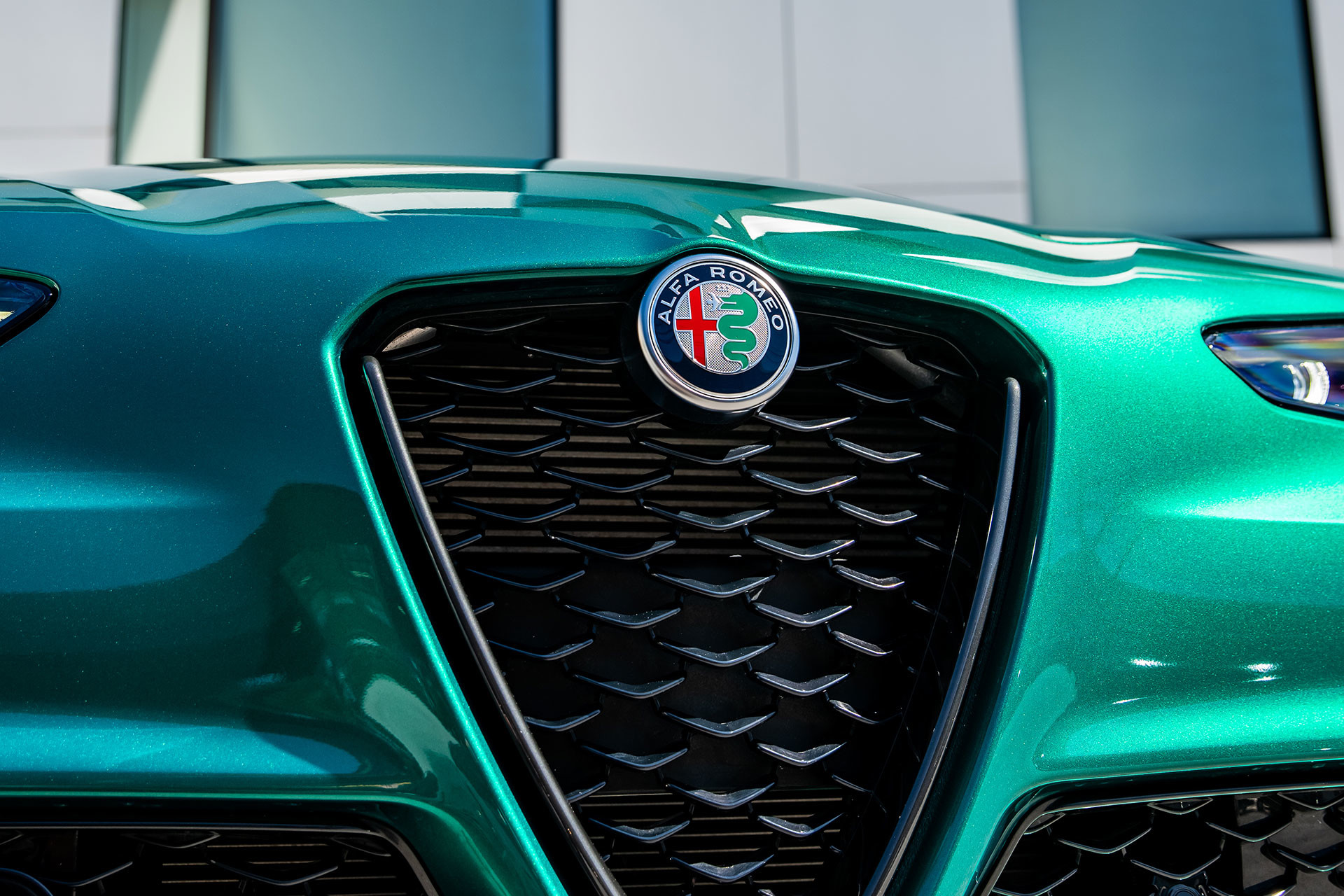 Front grille of a green 2026 Alfa Romeo Giulia with modern architectural background.