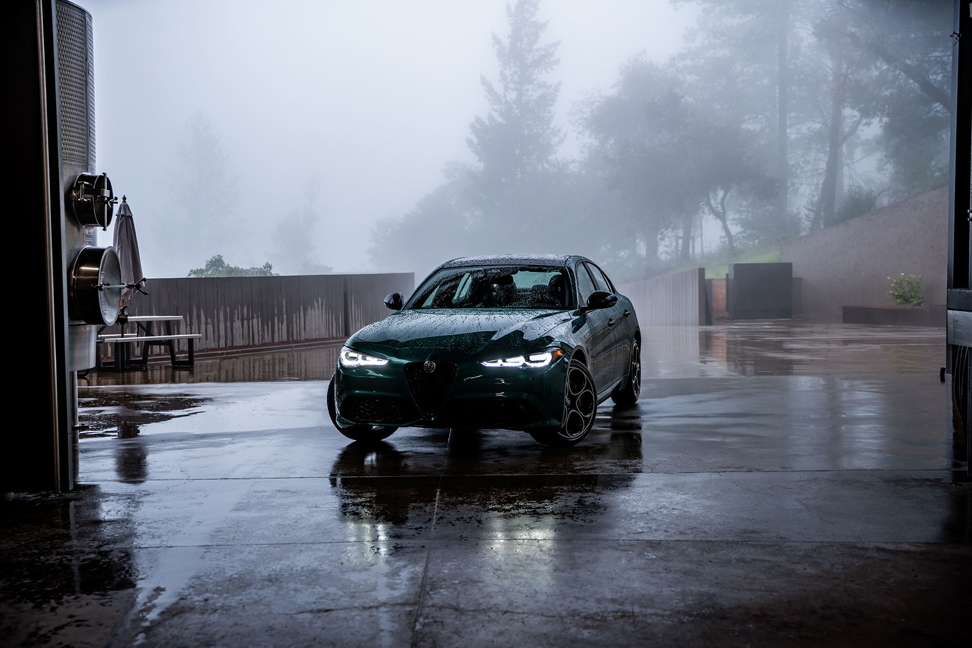 Green 2026 Alfa Romeo Giulia parked in a misty driveway with headlights on.