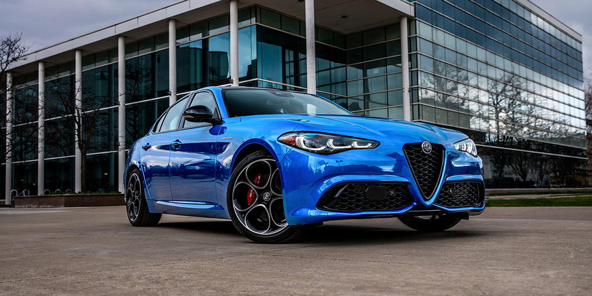 Blue 2026 Alfa Romeo Giulia parked in front of a modern glass building.