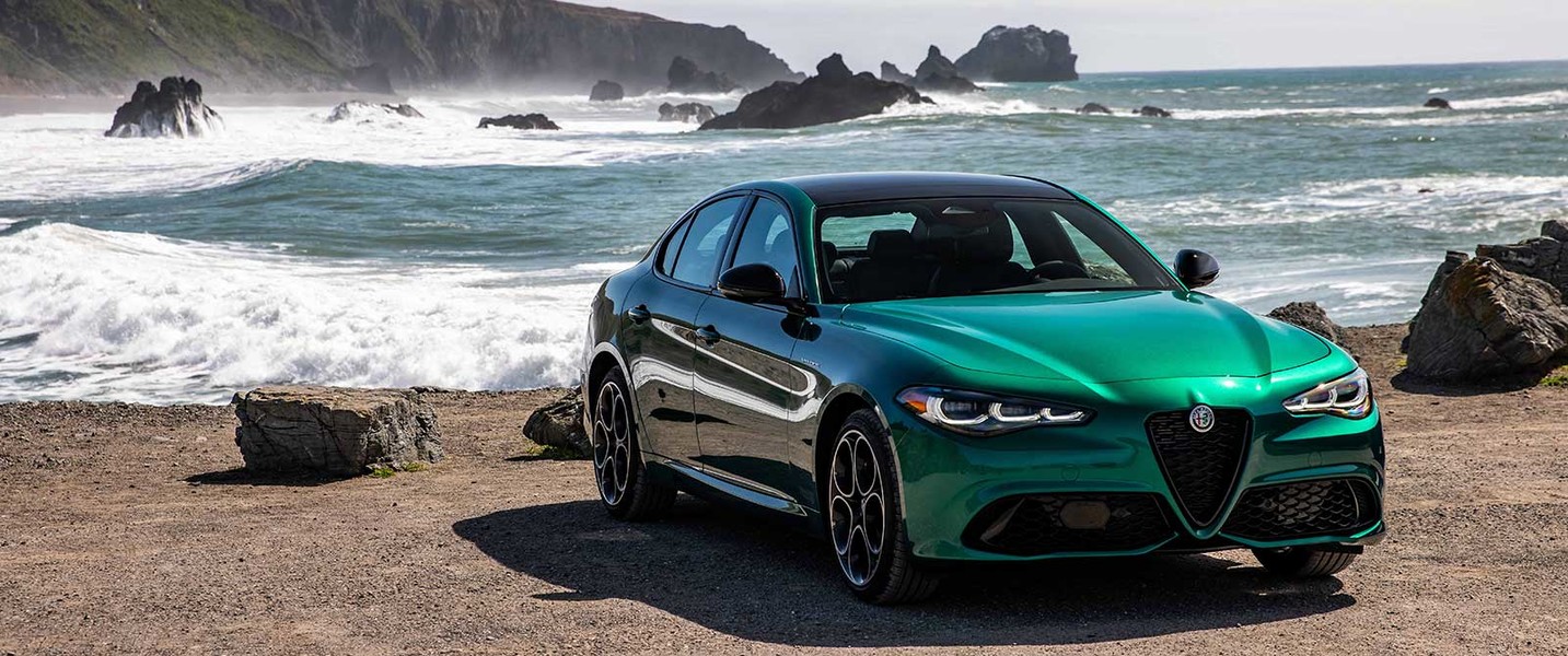 A green 2026 Alfa Romeo Giulia parked by the ocean with a scenic coastal view.