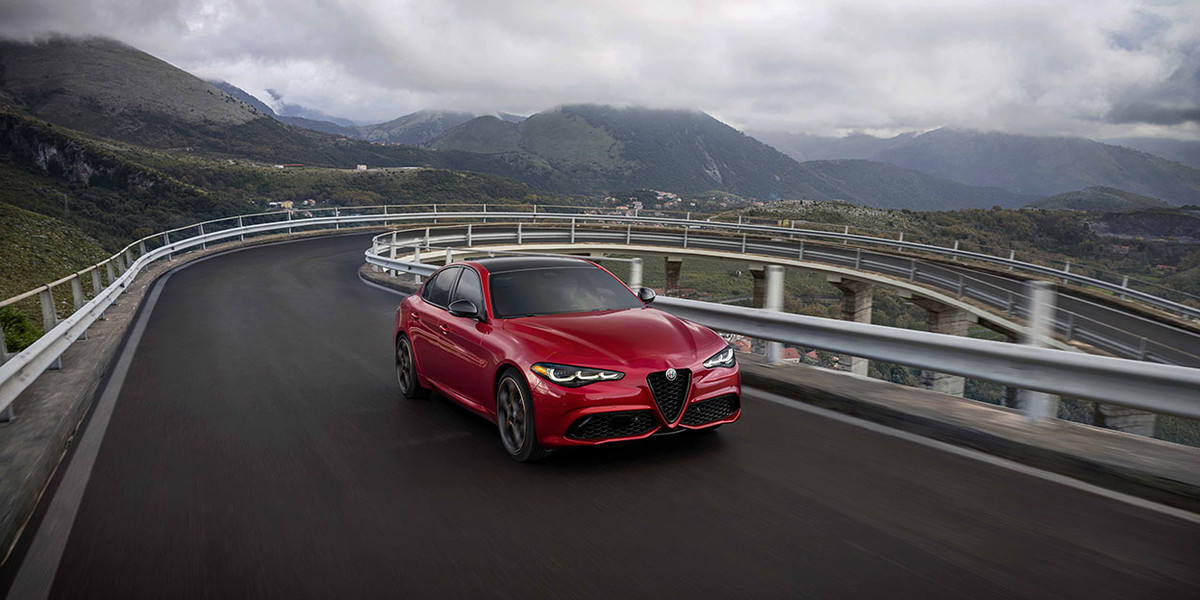 Red 2026 Alfa Romeo Giulia navigating a winding mountain road.