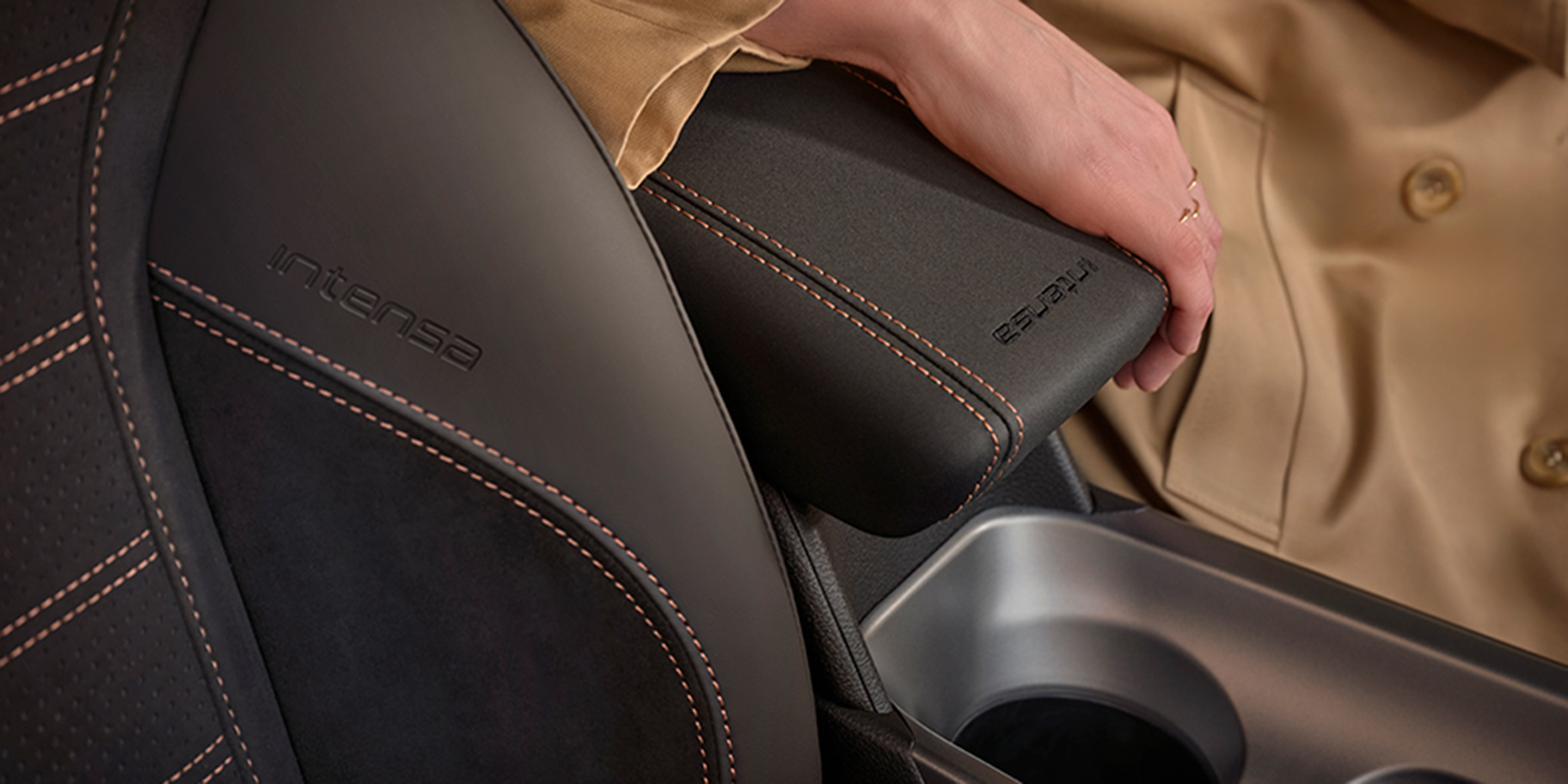 Un gros plan de l’intérieur d’une voiture Alfa Romeo avec la main d’une personne sur un accoudoir en cuir. 