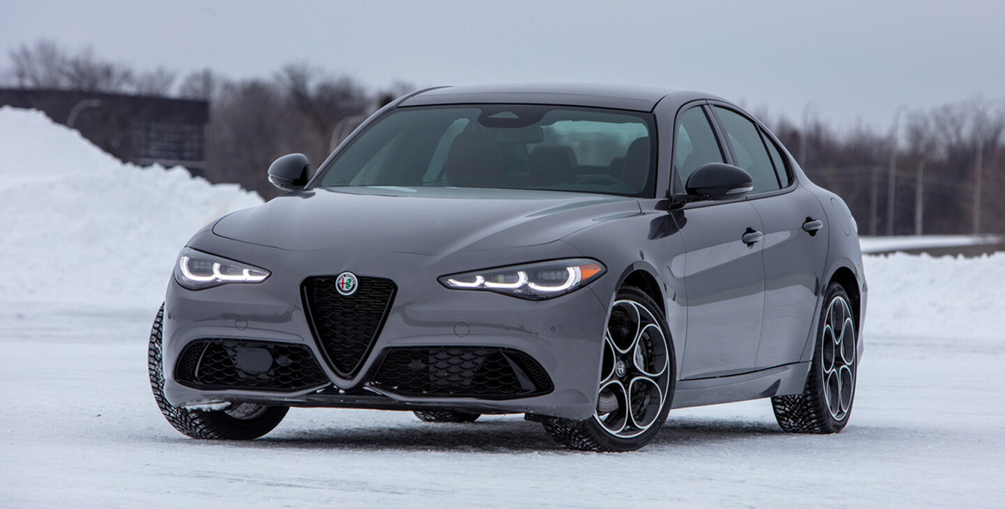 A grey 2026 Alfa Romeo Giulia parked in a snow-covered lot, showcasing its sleek design against a winter backdrop.