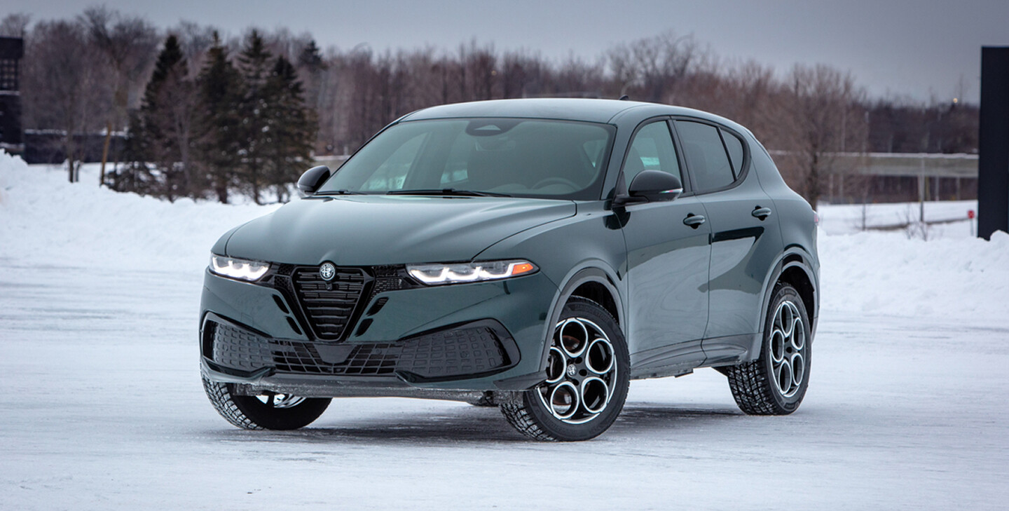 A Foresta Green 2026 Alfa Romeo Tonale parked in a snow-covered lot, showcasing its sleek design against a winter backdrop.