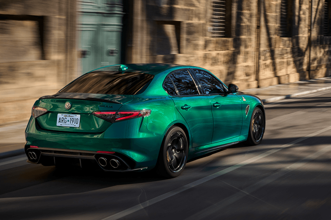 Vue arrière de l'Alfa Romeo Giulia Quadrifoglio 2024 roulant sur une route pavée.