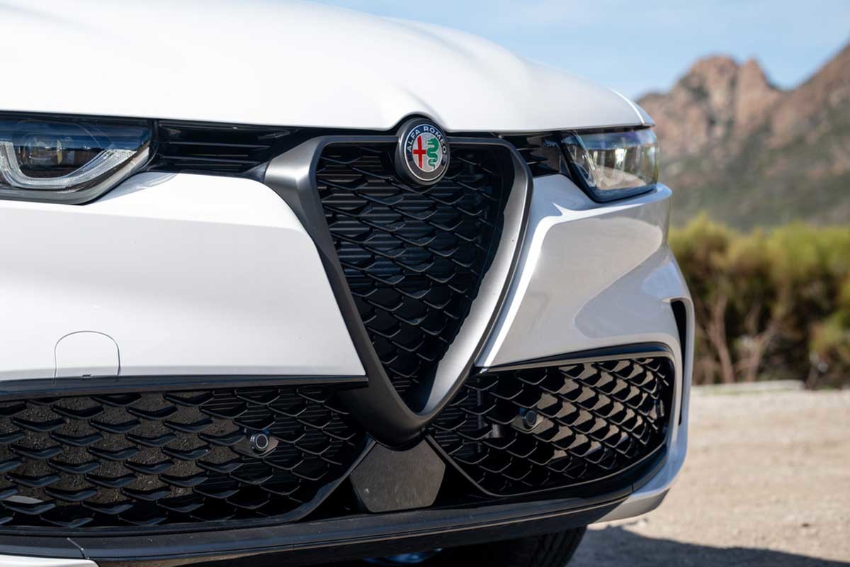 Close-up of a white 2025 Alfa Romeo Tonale badge, grille, and headlamps.