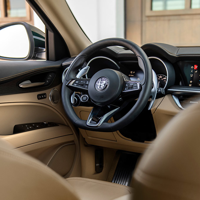 A close-up of the interior of the 2021 Alfa Romeo Stelvio Ti Lusso with crema luxury leather trim and light walnut wood accents.