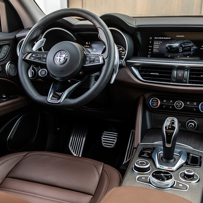 The front interior of the 2022 Stelvio featuring brown leather seats and black finishings 