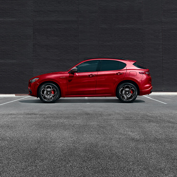 Side view of a parked red Alfa Romeo Stelvio.