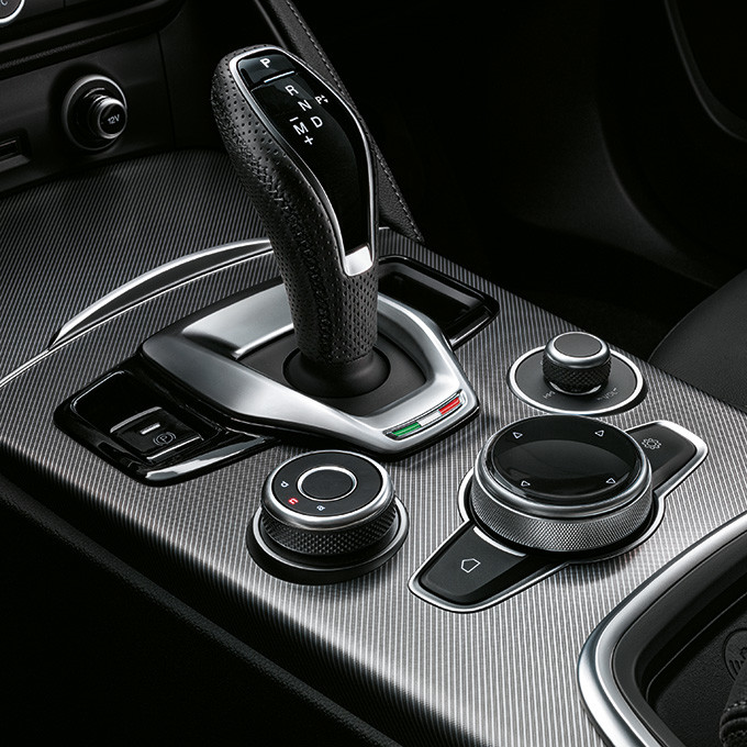 A closeup view of the gearshift and control dials inside of a 2024 Alfa Romeo Stelvio.
