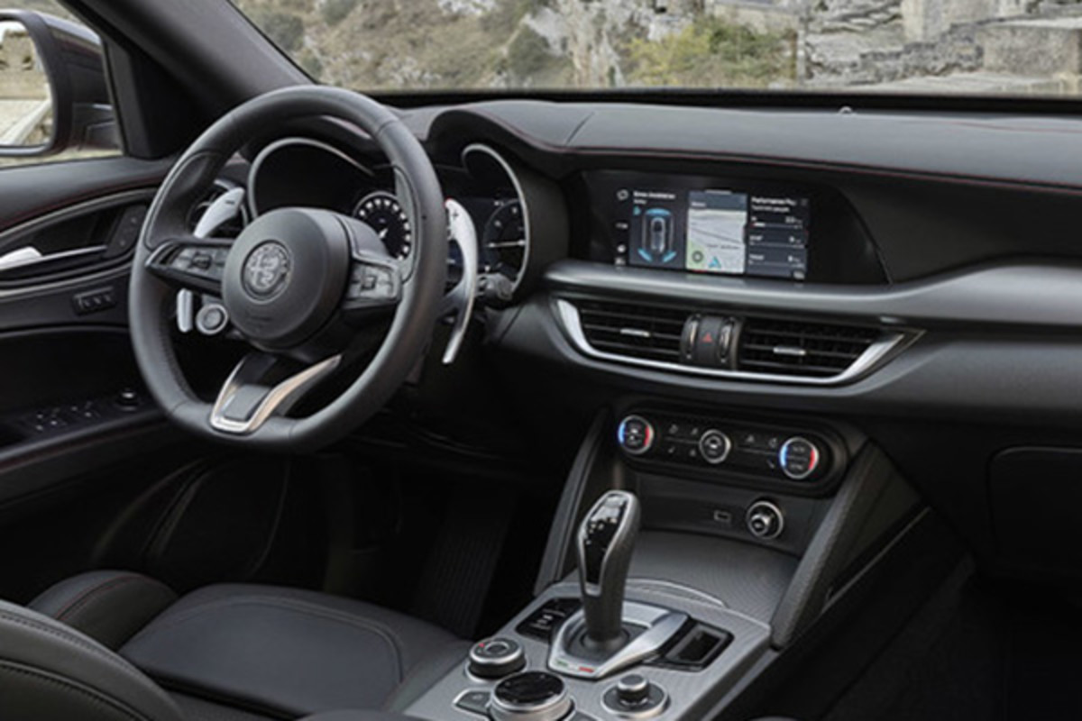 L'intérieur d'une Alfa Romeo 2025 est moderne et luxueux, tandis que l'extérieur offre une vue sur l'architecture historique en pierre. L'habitacle dispose d'un tableau de bord élégant avec écran tactile central, d'un volant sport et d'élégants sièges en cuir.