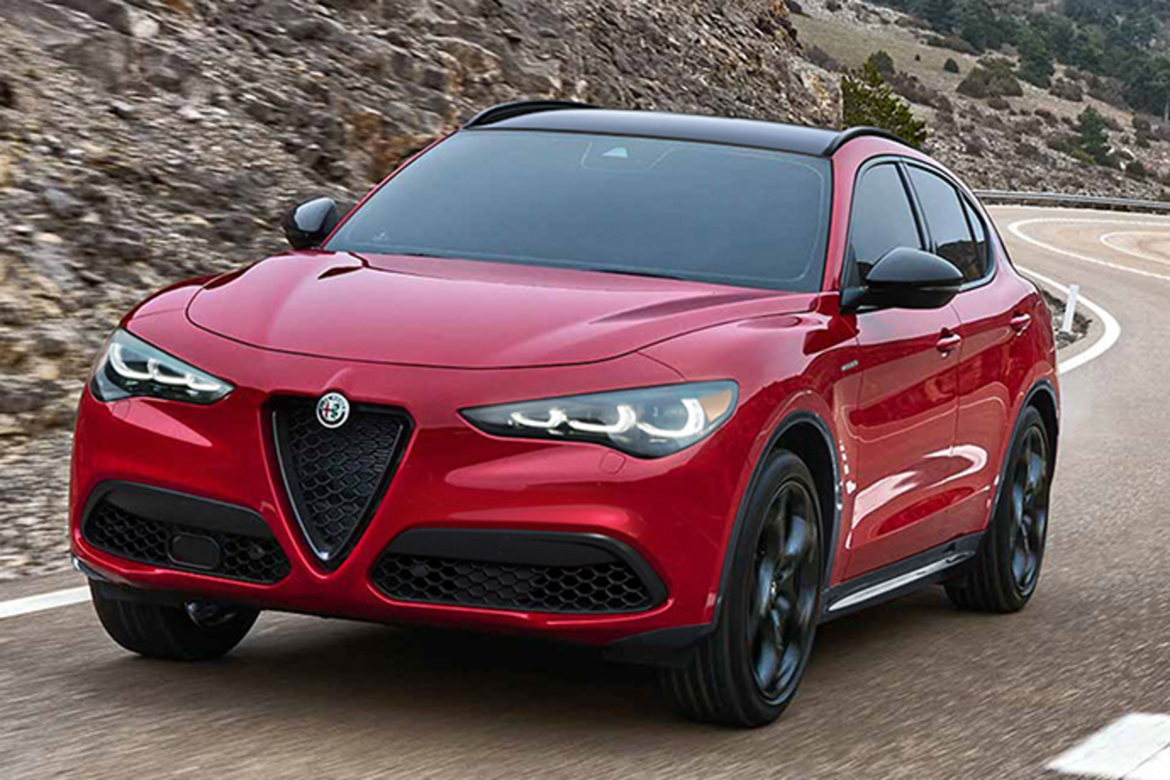 Une Alfa Romeo rouge 2025 circulant sur une route panoramique.