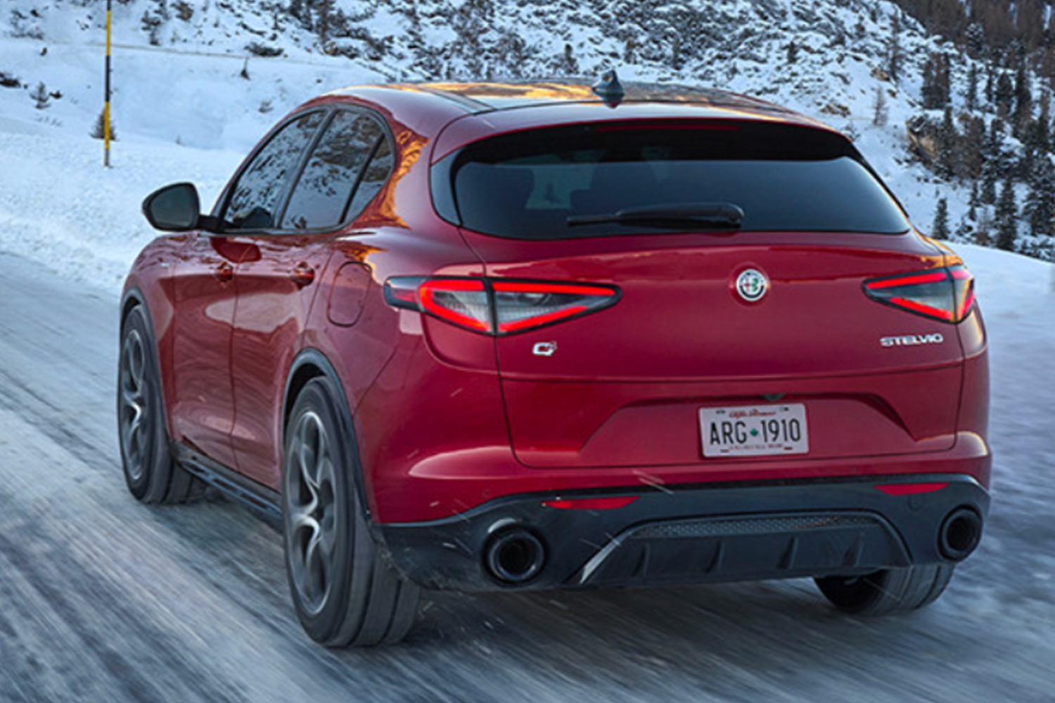Une Alfa Romeo Stelvio rouge 2025 traversant un paysage enneigé.