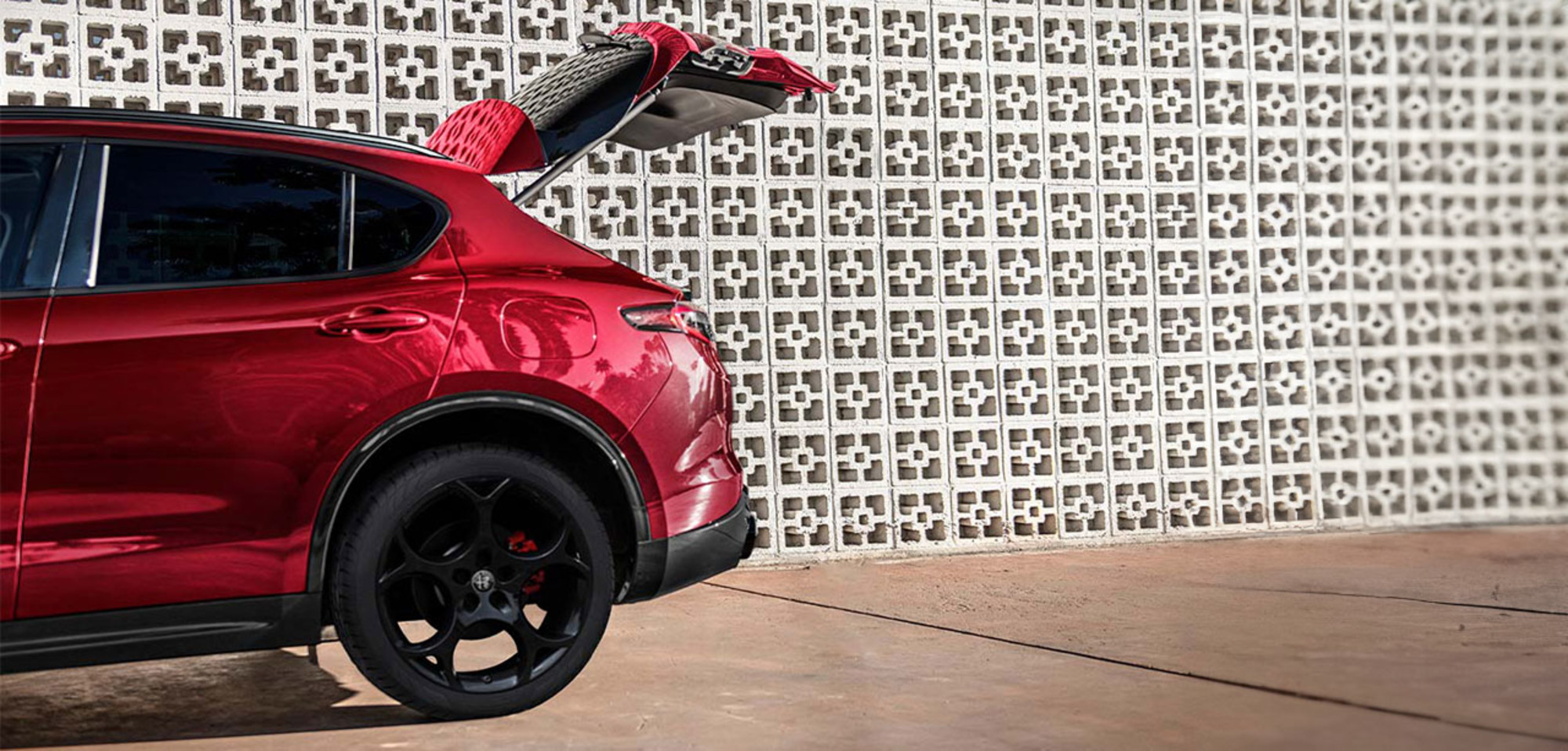 Une vue partielle d'une Alfa Romeo Stelvio 2025 rouge avec le portail du coffre ouvert.