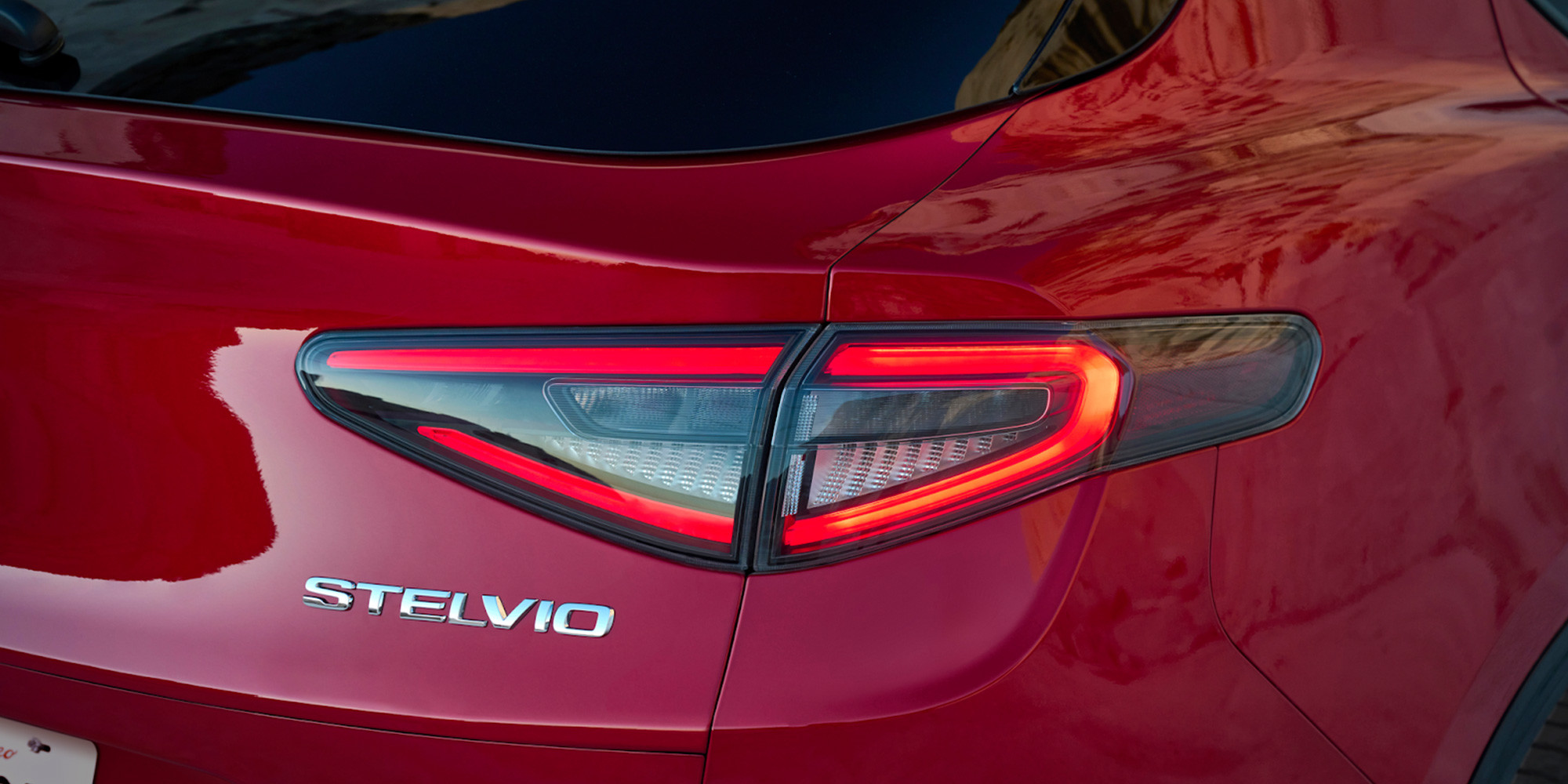 Gros plan d'une Alfa Romeo rouge 2025, mettant l'accent sur le design élégant des feux arrière du modèle Stelvio.