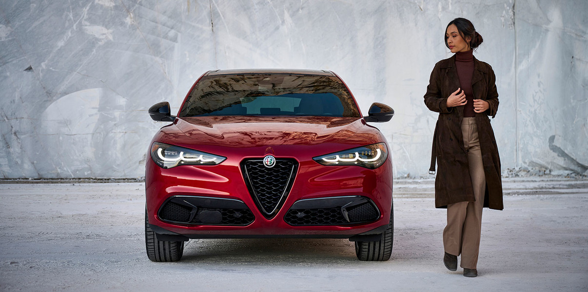 Une personne vue s’éloigner d’une Alfa Romeo Stelvio 2025 rouge.