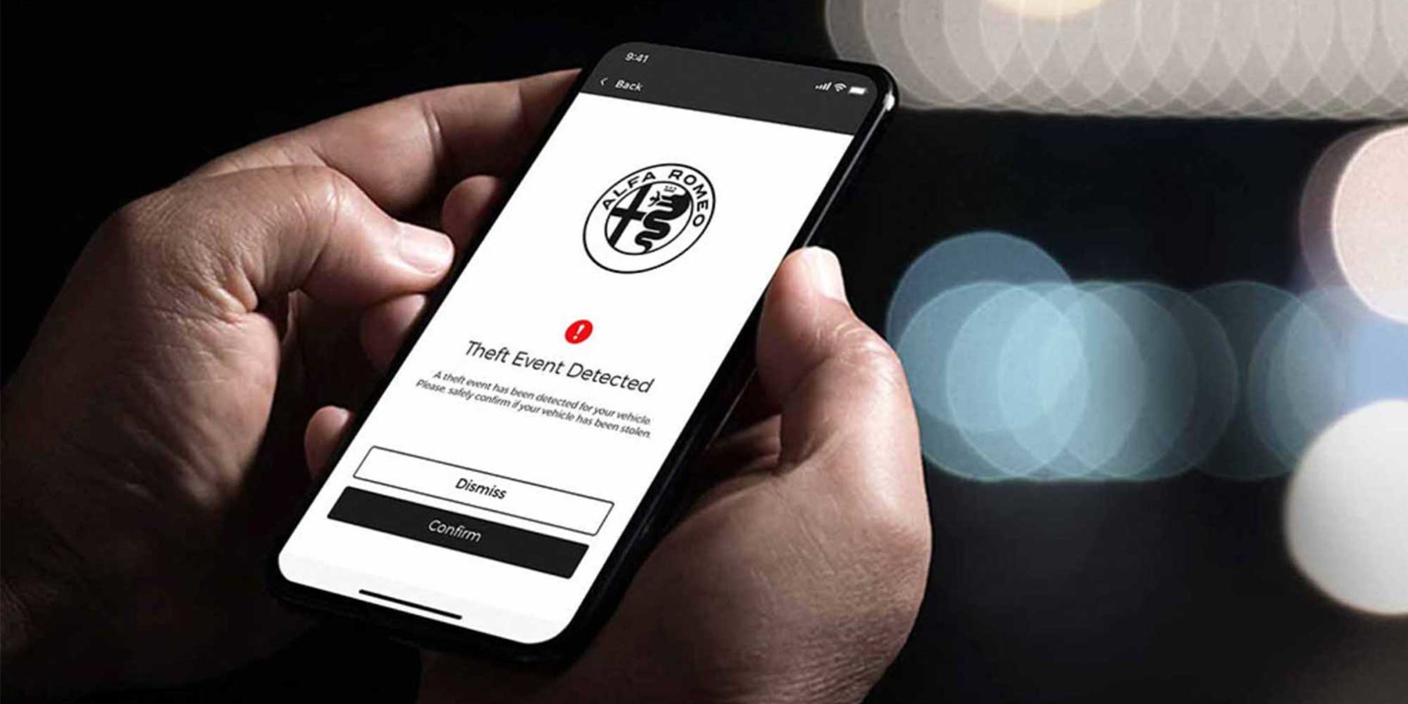 Close-up of a smartphone displaying the Alfa app, used to control the 2026 Alfa Romeo Stelvio, with a notification about a detected theft event.