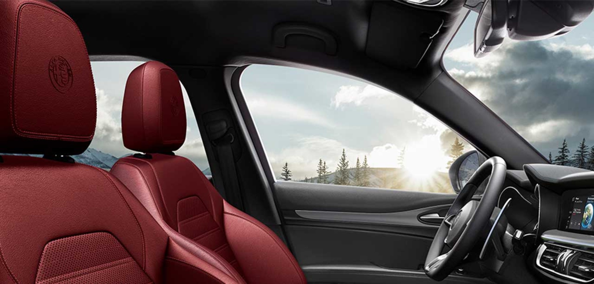 Interior of the 2026 Alfa Romeo Stelvio with red leather seats, showcasing the dashboard, steering wheel, and a scenic view through the window.
