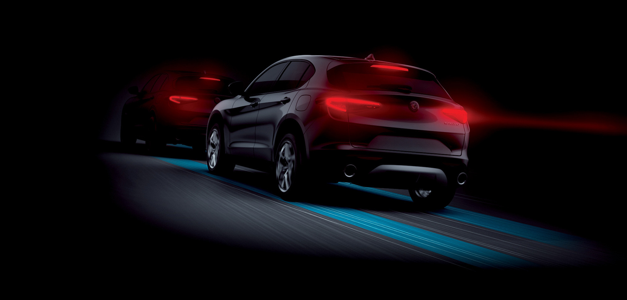 Rear view of two 2026 Alfa Romeo Stelvio vehicles driving on a darkened road, illustrating the forward collision warning plus activated.