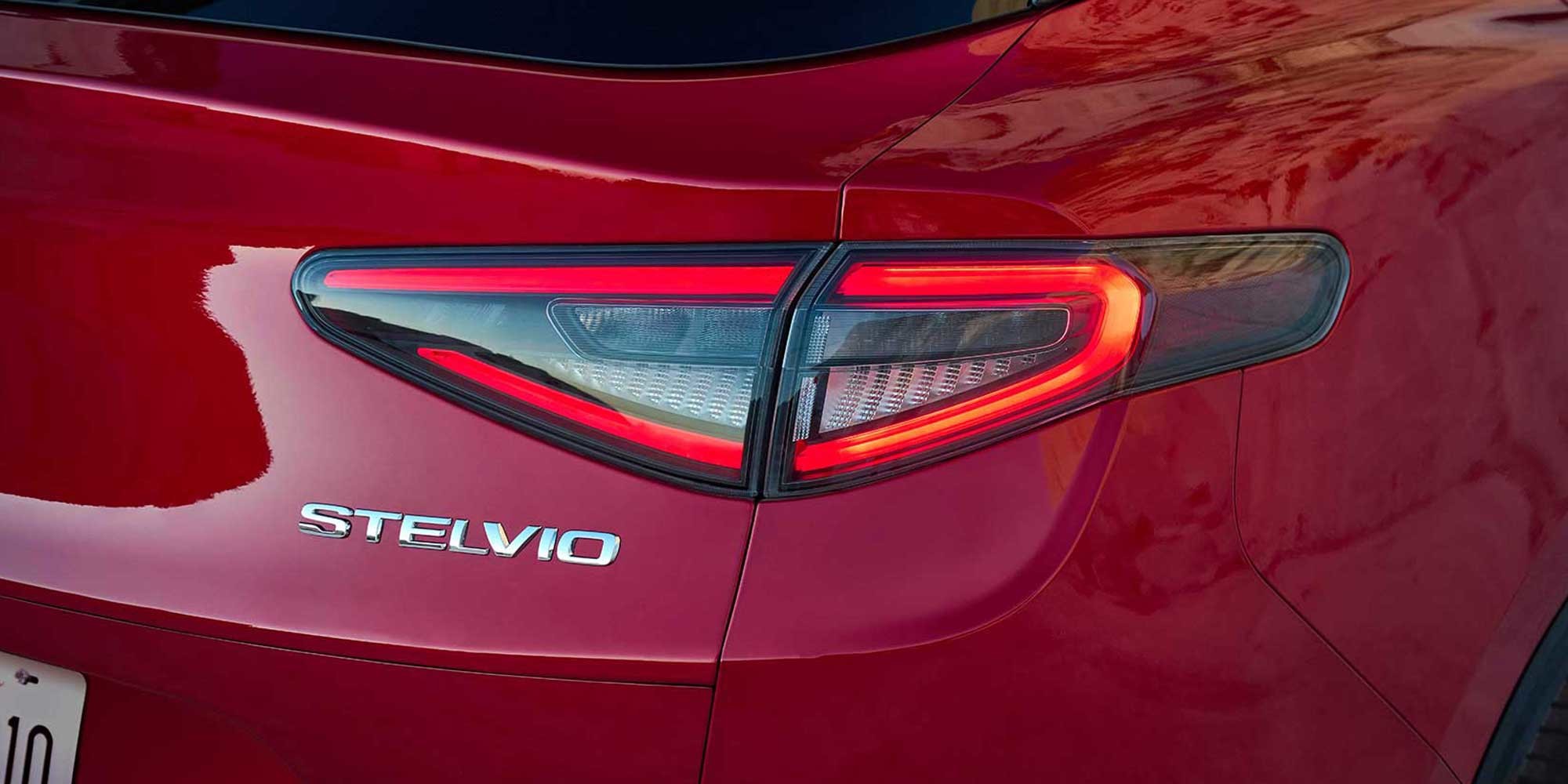 A close-up view of the badge and taillight design on a red 2026 Alfa Romeo Stelvio.