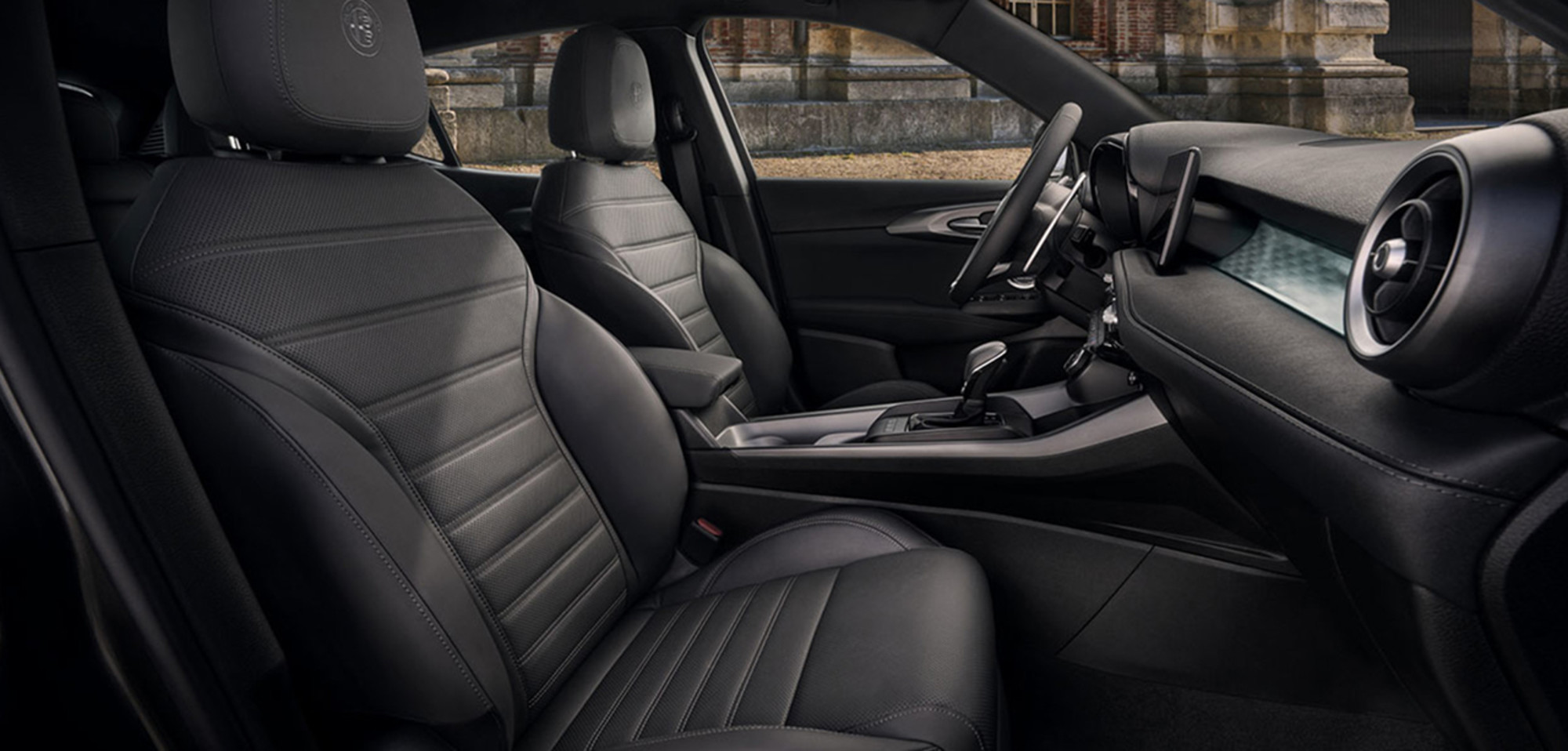 Vue de l’intérieur de l’Alfa Romeo Tonale 2025, avec ses sièges avant en cuir et son tableau de bord moderne.