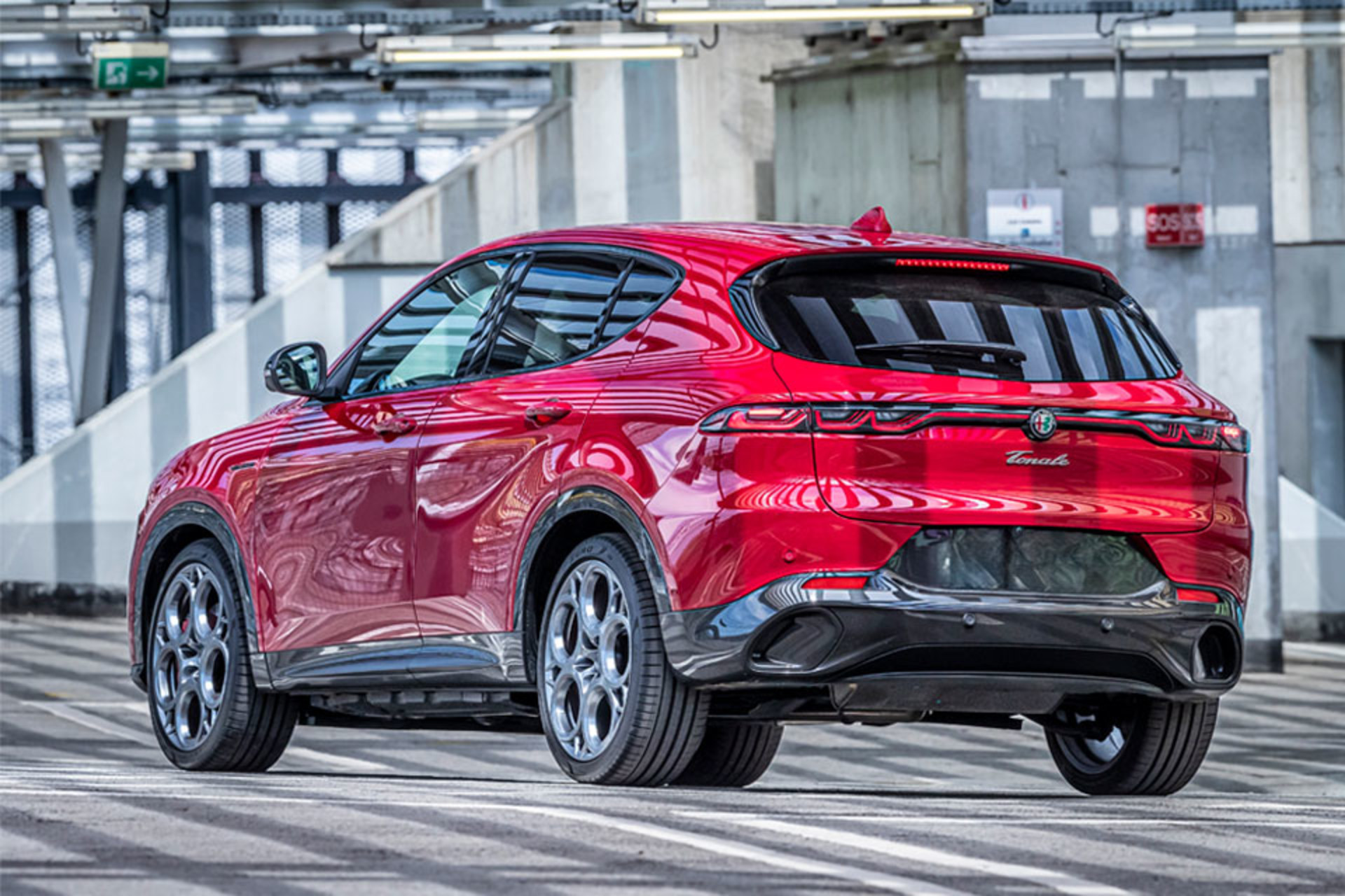 Vue arrière de l’Alfa Romeo Tonale 2025 de couleur Alfa Rosso stationné dans une rue de la ville.