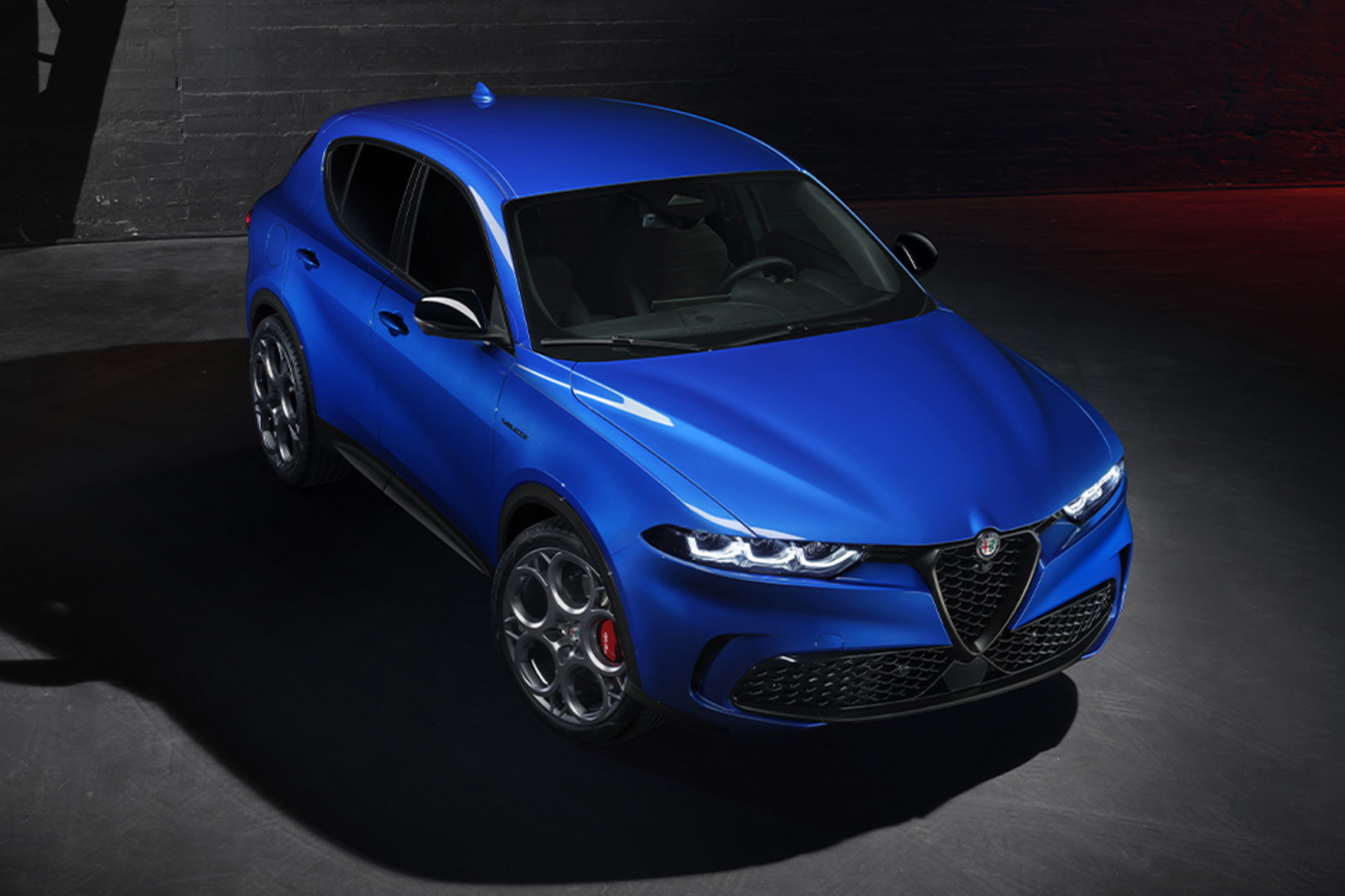 Alfa Romeo Tonale 2025 de couleur bleu Misano métallisé stationné dans un environnement industriel faiblement éclairé.