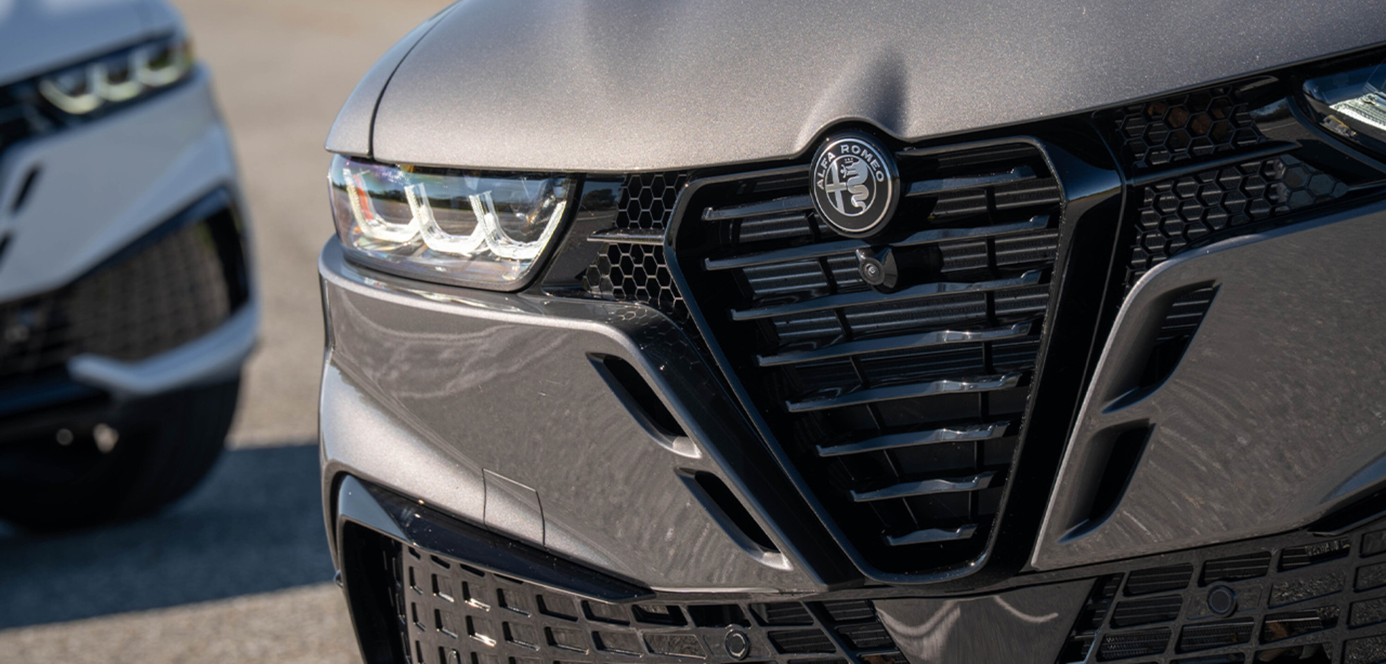 Gros plan sur un Alfa Romeo Tonale à essence gris 2026, mettant en valeur la calandre et les phares distinctifs, soulignant son design élégant et moderne.