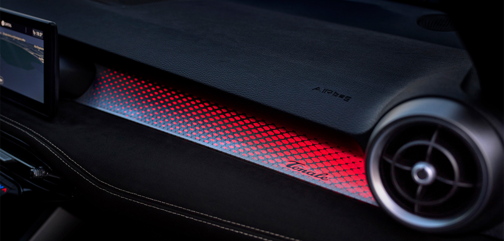 Vue intérieure d'un Alfa Romeo Tonale à essence 2026 présentant un tableau de bord au design élégant, avec des accents rouges illuminés et un style de ventilation moderne.