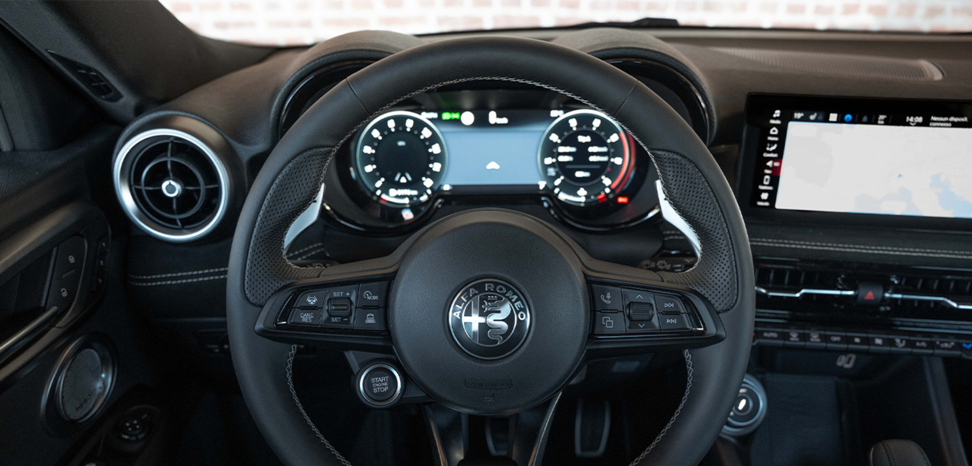 Intérieur d'un Alfa Romeo Tonale à essence 2026 avec volant sport à commandes intégrées, tableau de bord numérique et écran d'infodivertissement moderne, soulignant le design axé sur la technologie du véhicule.