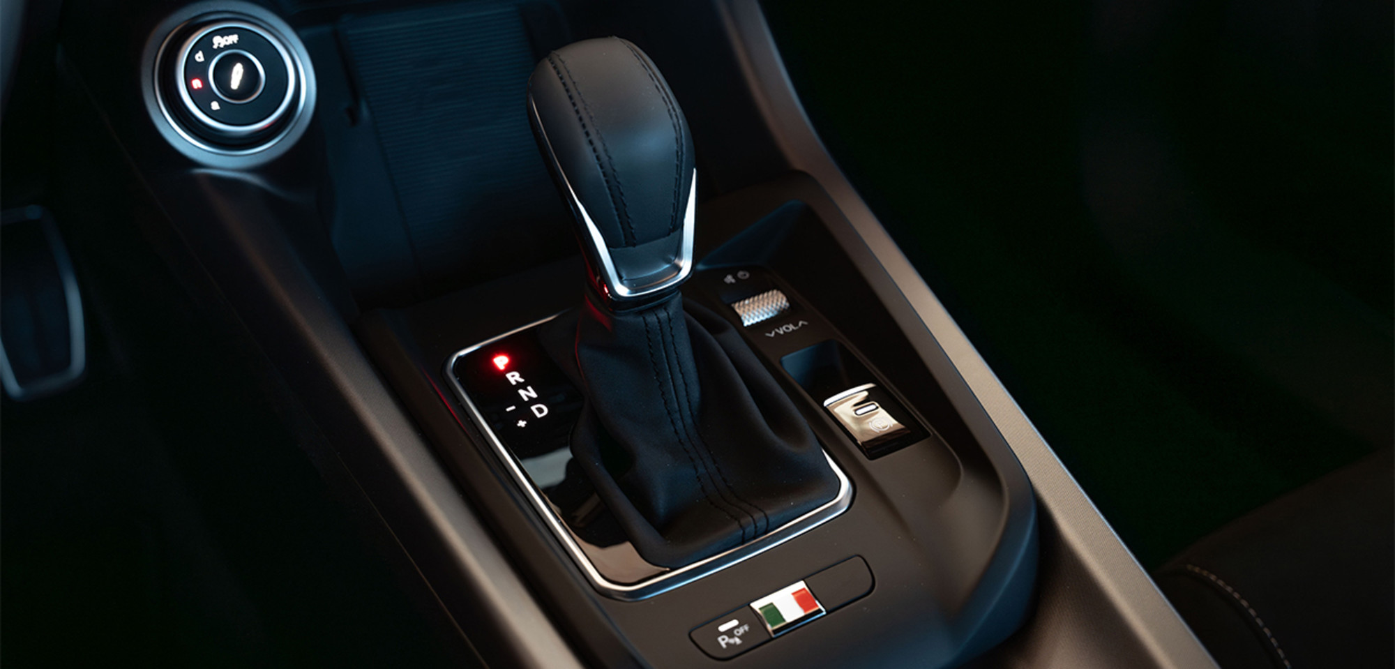 Intérieur d'un Alfa Romeo Tonale à essence 2026 mettant en valeur le levier de vitesses, avec des commandes élégantes et des détails aux couleurs du drapeau italien, soulignant l'attention portée au design et à l'héritage du véhicule.