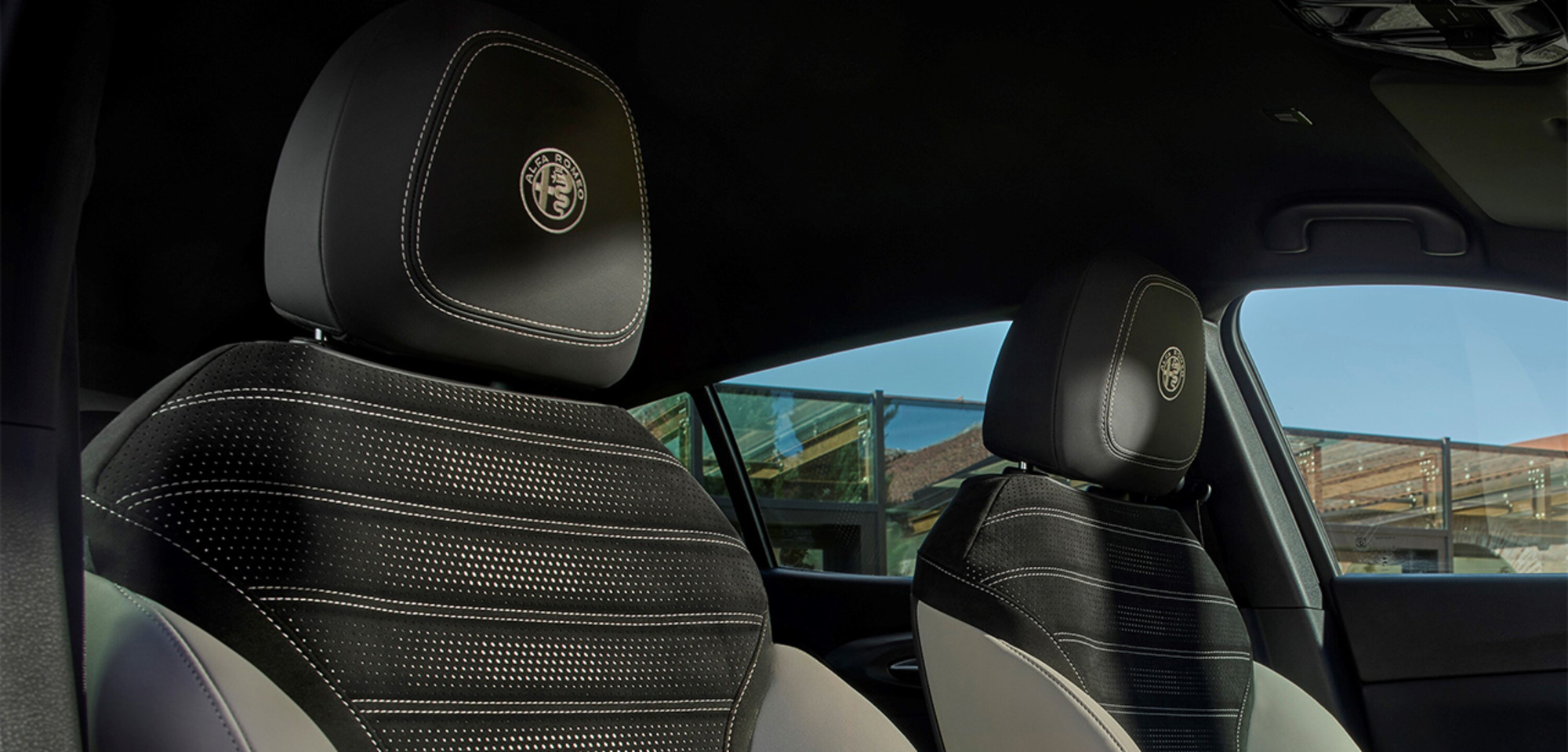 Intérieur d'un Alfa Romeo Tonale à essence 2026 présentant des sièges haut de gamme en cuir perforé élégant avec des surpiqûres détaillées, mettant l'accent sur le confort et le luxe.