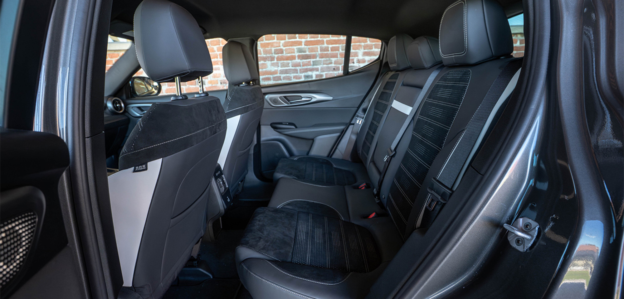 Intérieur d'un Alfa Romeo Tonale à essence 2026 mettant en valeur les sièges arrière spacieux avec des matériaux haut de gamme et des surpiqûres détaillées, soulignant le confort et l'élégance.