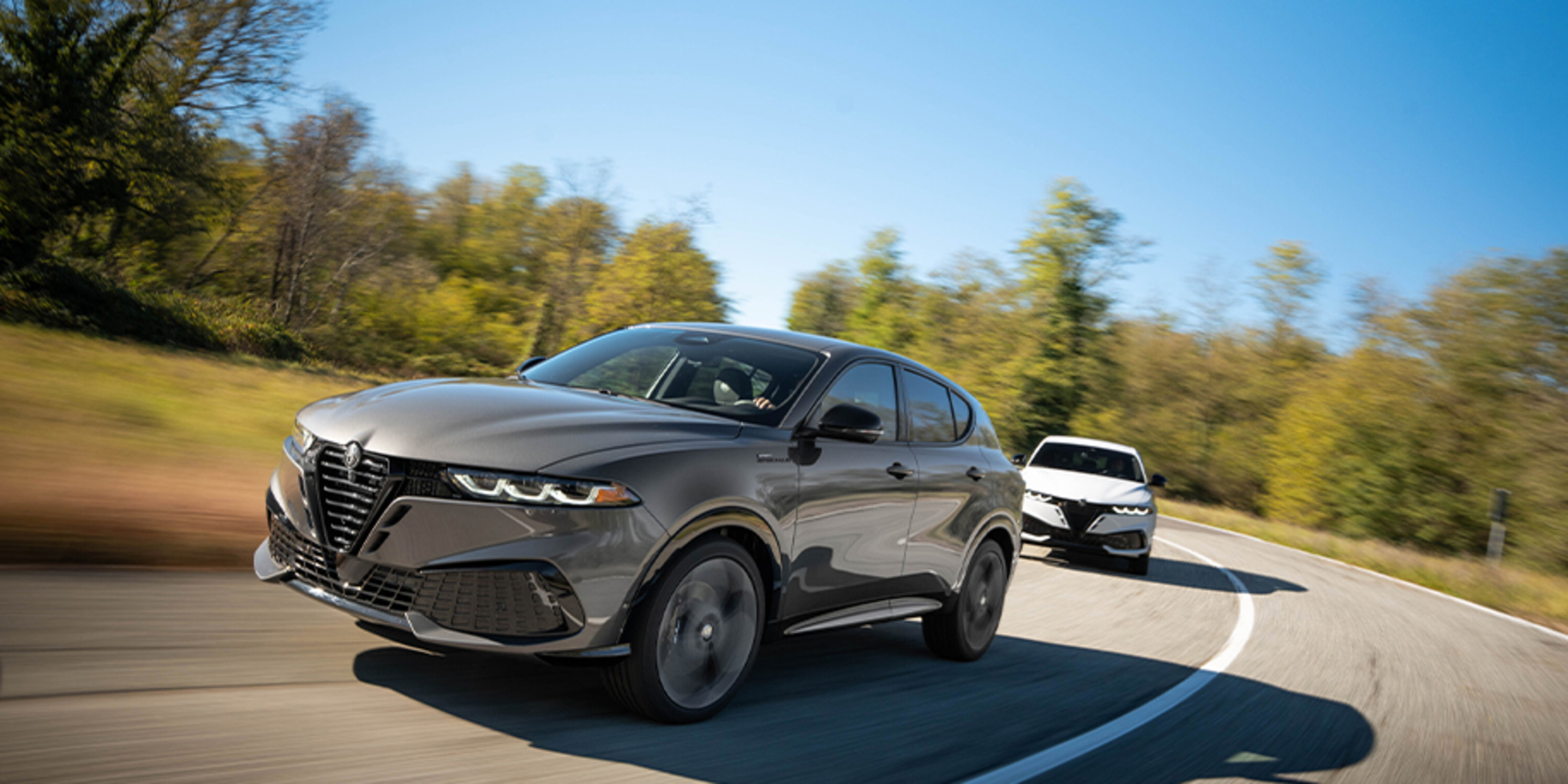 View of a grey Alfa Romeo Tonale driving on a winding road, with another Tonale following behind.