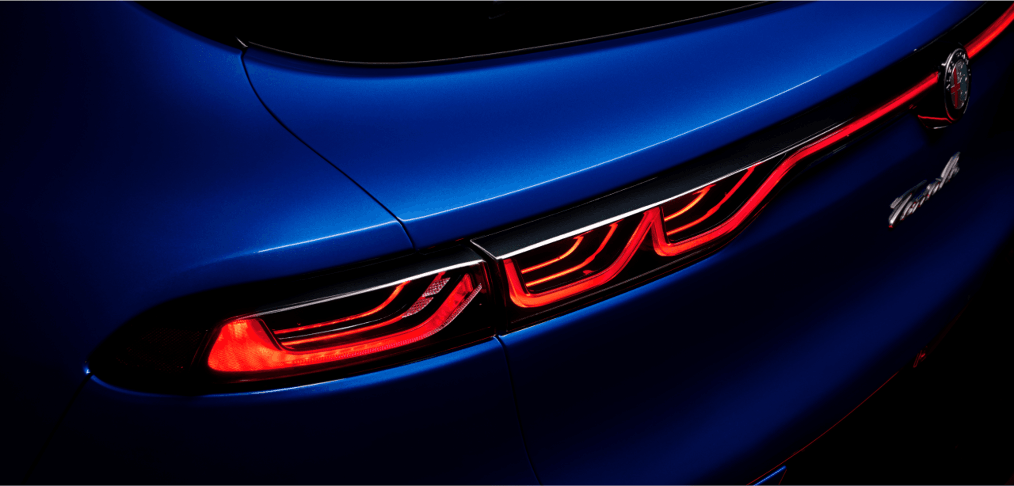 Gros plan des feux arrière gauche d'une Alfa Romeo Tonale VHR de couleur bleu Misano métallisé 2025, mettant en valeur le design élégant et les feux arrière éclairés.