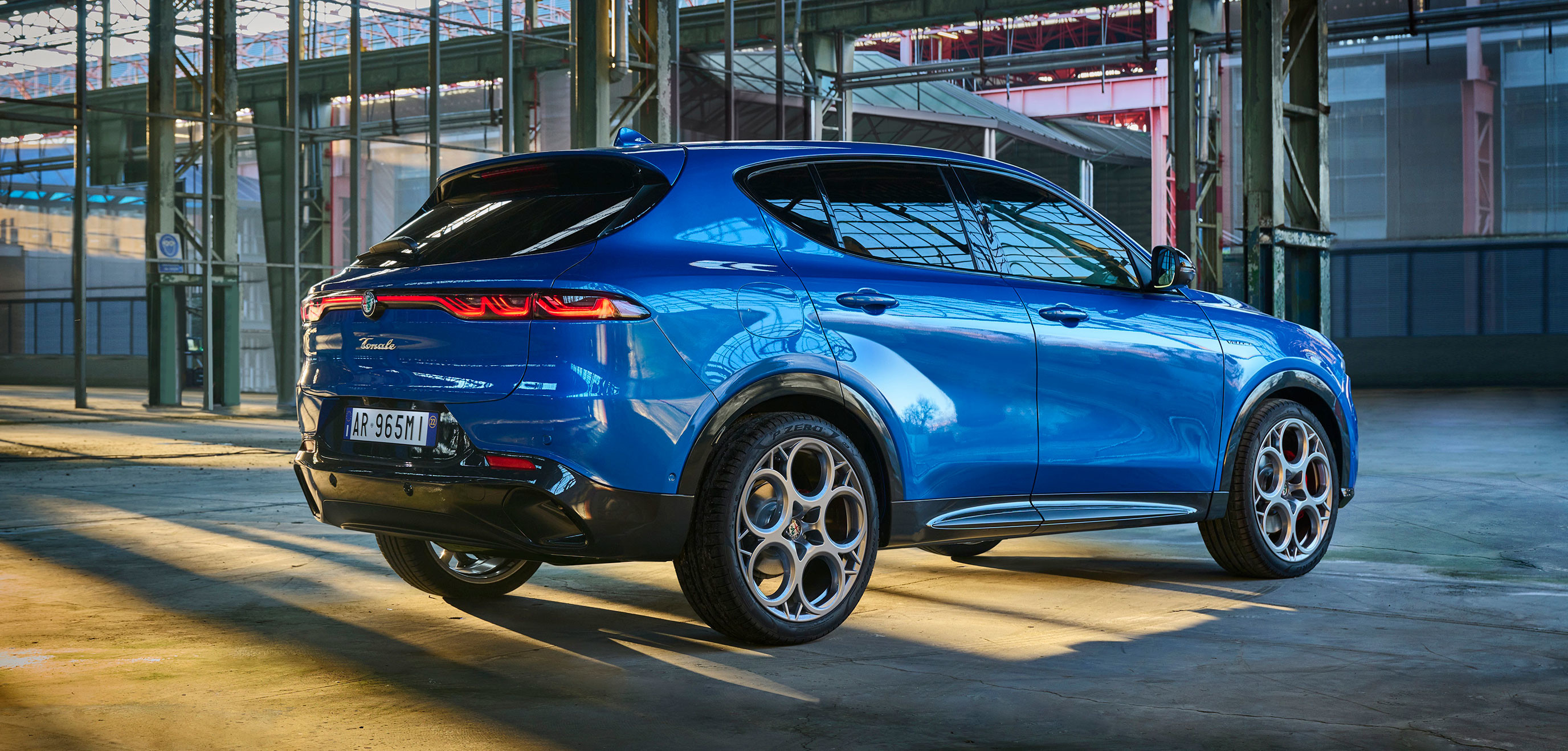 Alfa Romeo Tonale VHR 2025 de couleur bleu Misano métallisé garé à l'intérieur d'un entrepôt industriel.