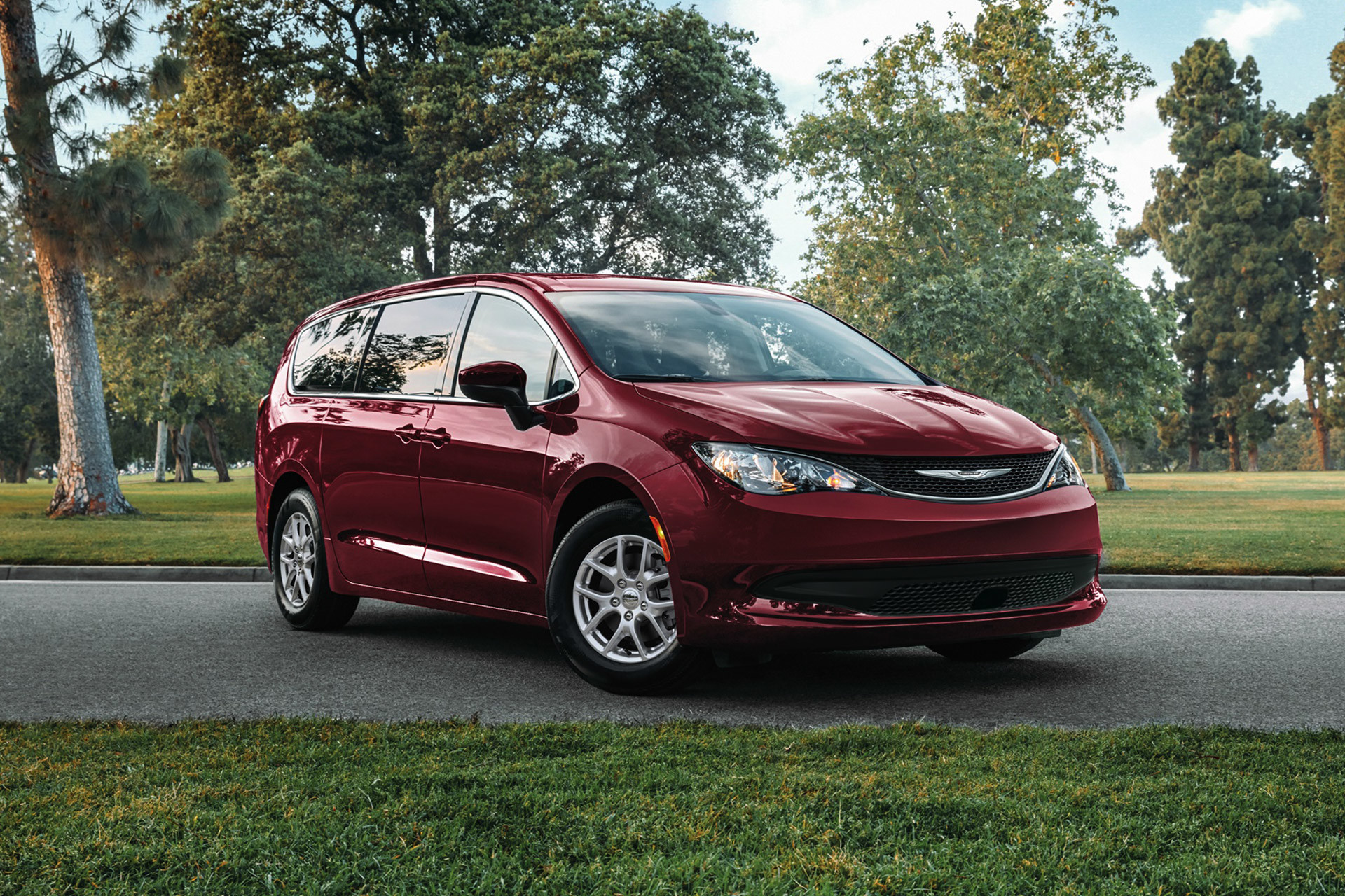 A three-quarters view of a Velvet Red Pearl 2021 Chrysler Grand Caravan parked on a road with a forest in the background.