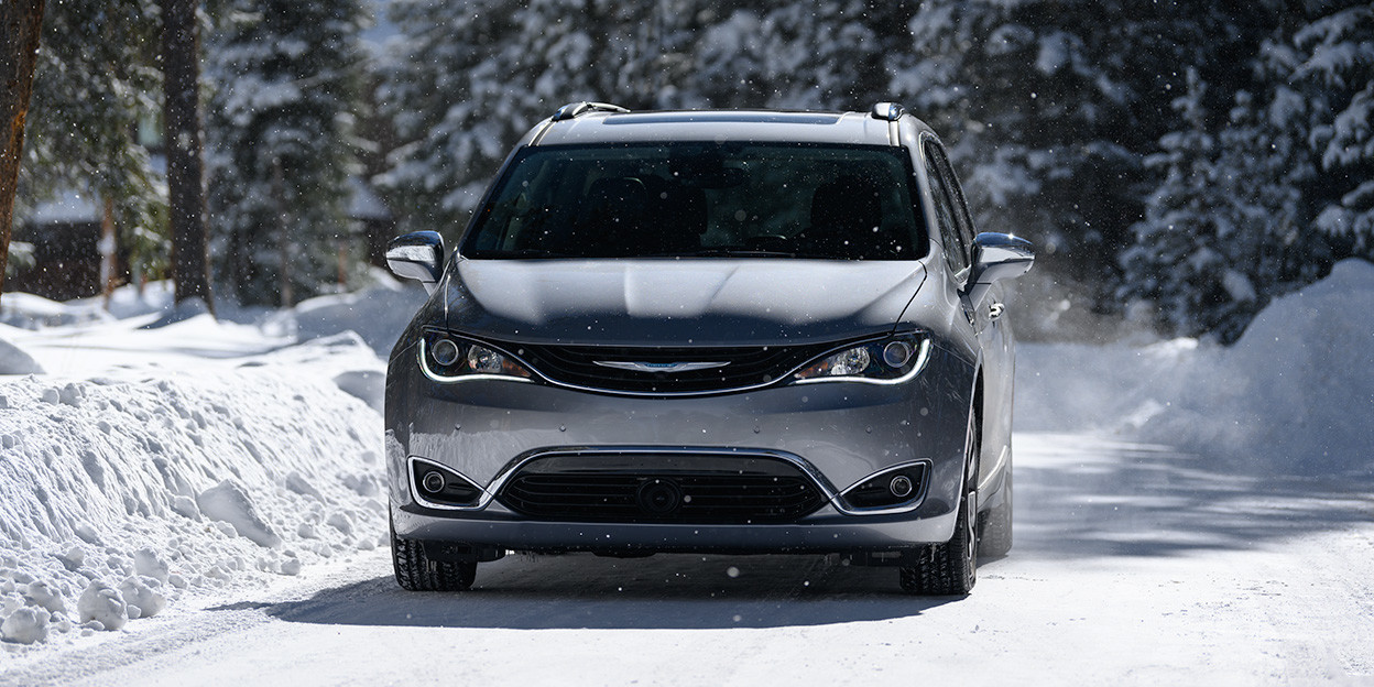 Front view of the silver 2019 Chrysler Pacifica Hybrid in a snowy forest