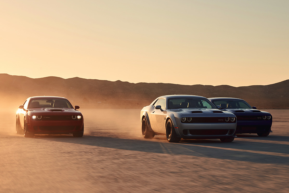 Three 2020 Dodge Challengers being driven on a desert beside each others