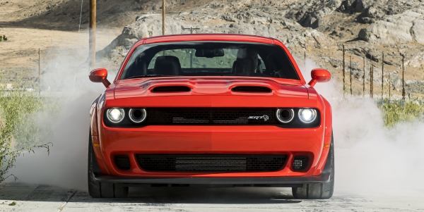 Vue de face d'un Dodge Challenger 2021 rouge roulant sur une route de terre.
