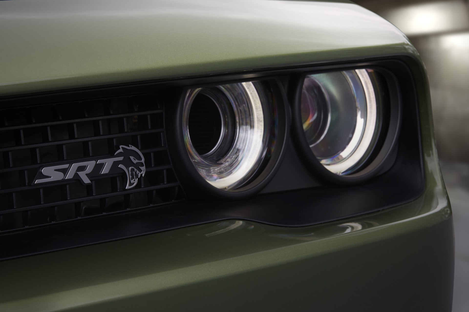 2022 Challenger SRT Hellcat Redeye Widebody Jailbreak in F8 Green, exterior close up of illuminated headlight and SRT badging on grille.