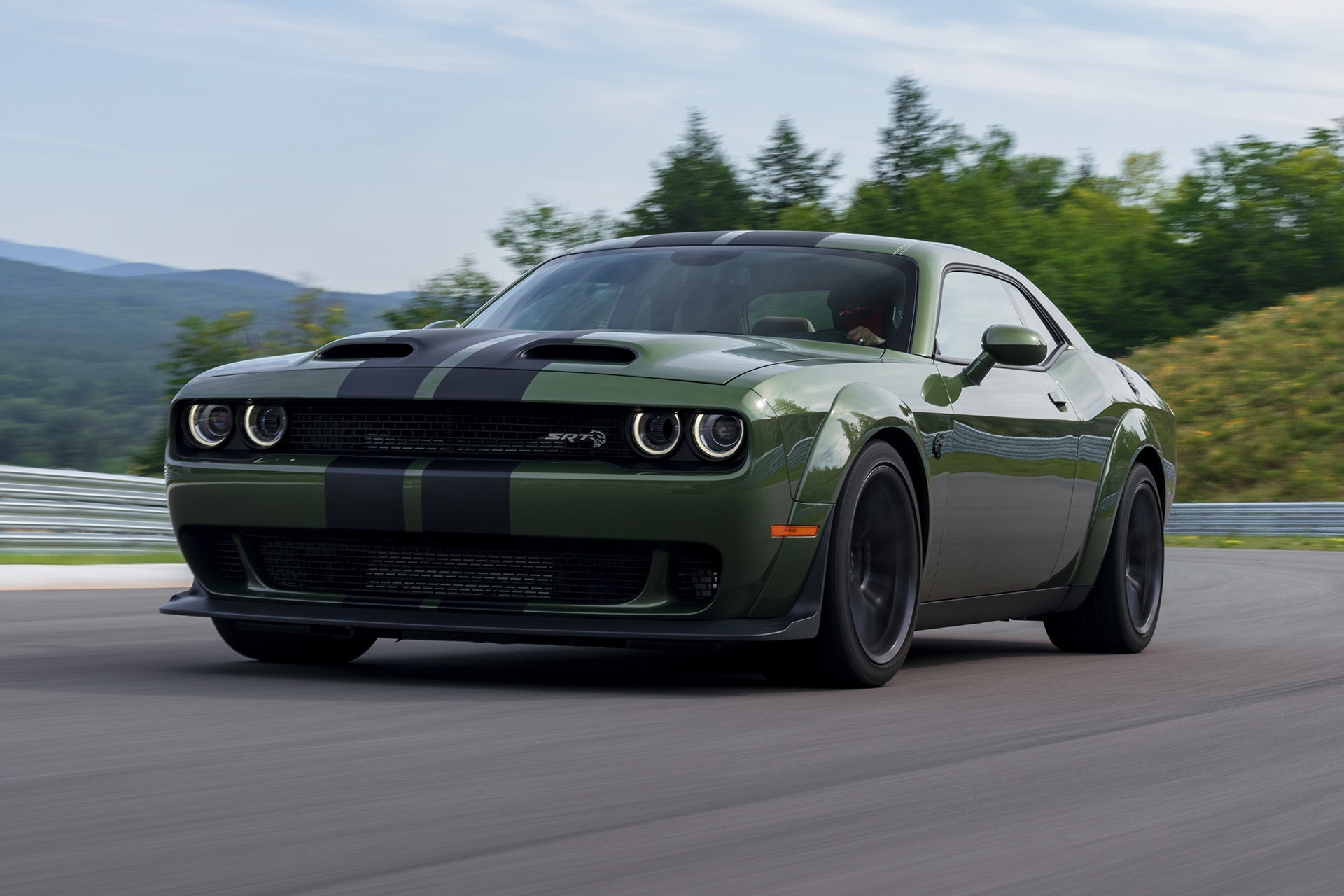A green 2022 Dodge Challenger, being driven through a curved road on a track.